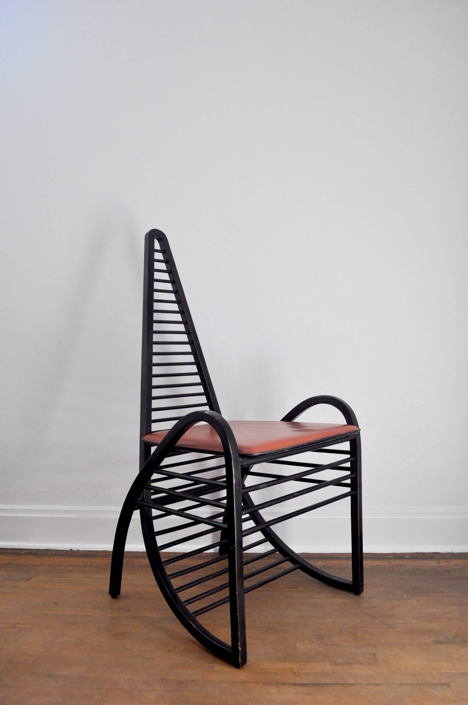 Dynamic 1980s Italian postmodern chair with a continuous gesture in form articulated in painted black wood with a rust-colored leather seat.
  