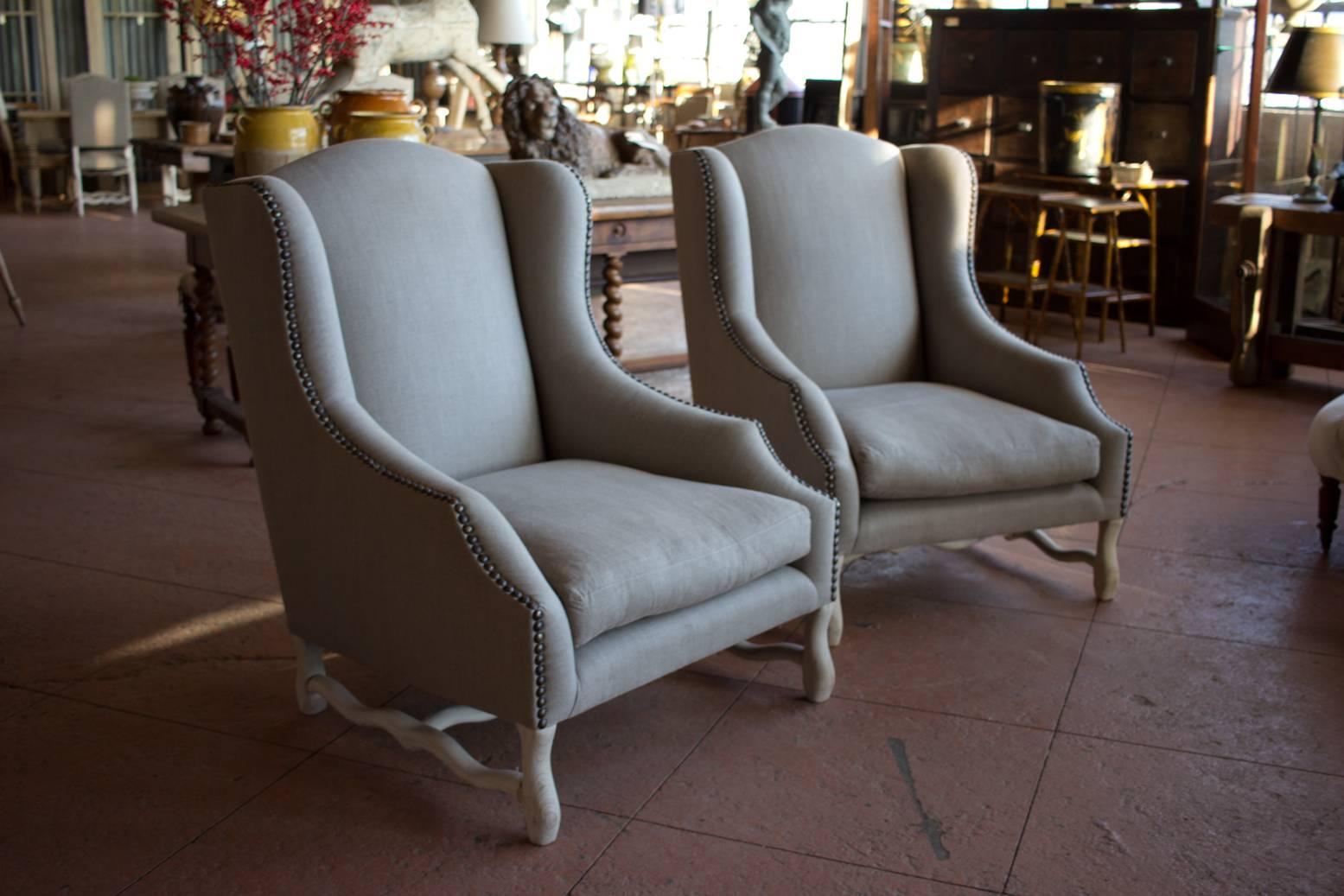 Pair of large-scale down filled antique Os du Mouton bergères chairs. The legs have a newly limed finish. The newly upholstered French linen and brass studded chairs are down filled.