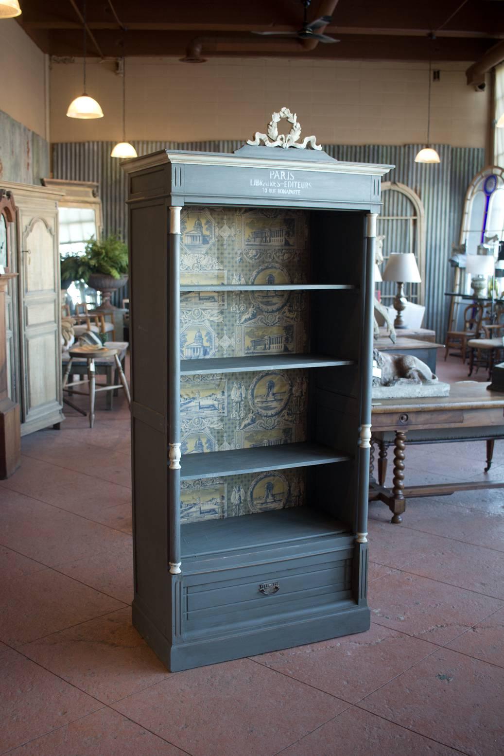 Very decorative antique French open shelved library cupboard or bookcase with architectural flanked columns and drawer to bottom. It has later paint and the back has been wallpapered with antiqued paper.