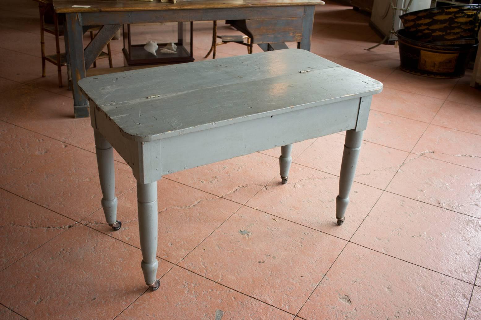 This is an unusual painted American mercantile desk or table on casters. Half the top flips up for storage. Great kitchen piece.