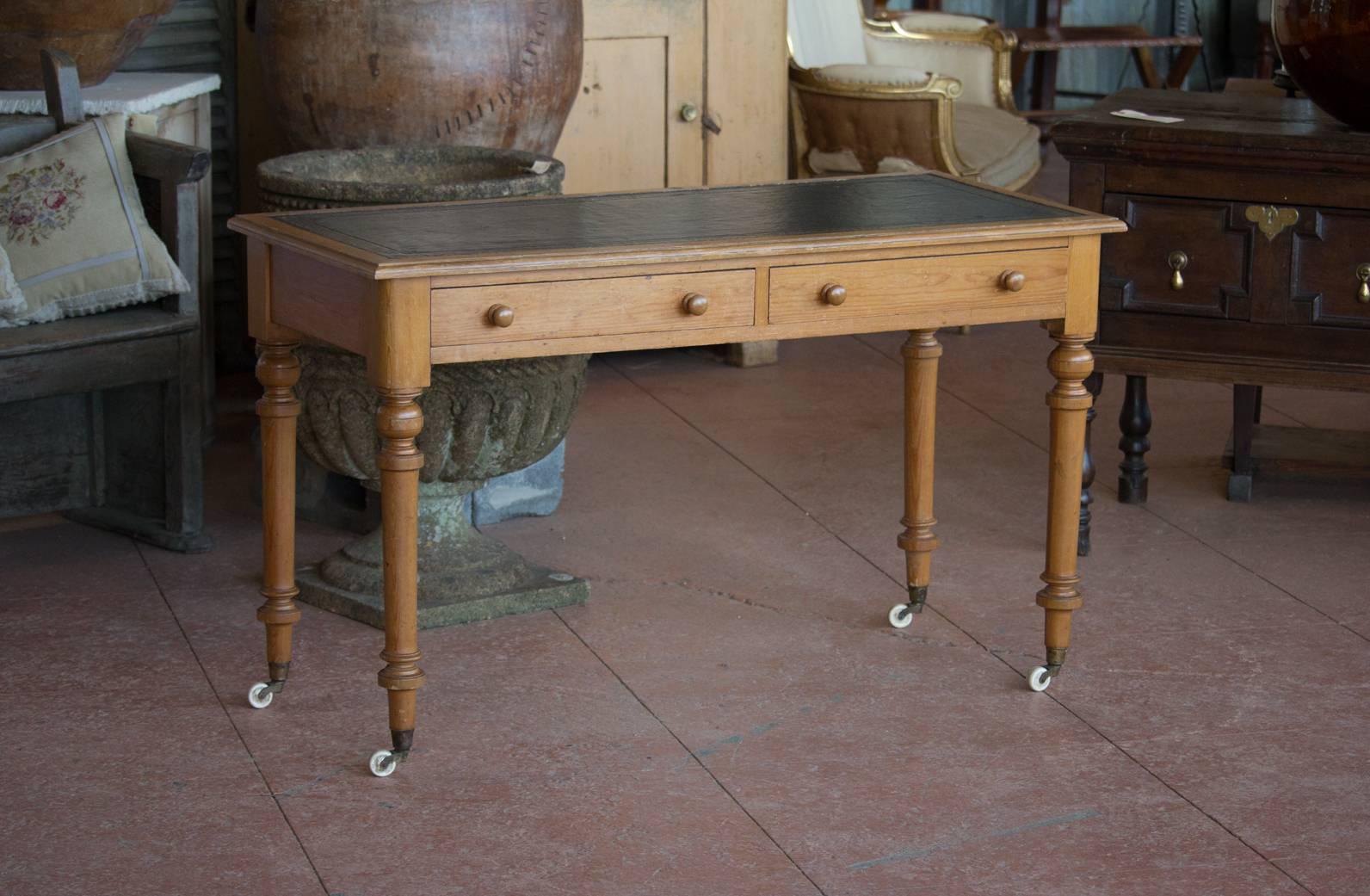 Antique English tooled dark blue leather top desk. The desk is on lovely turned legs with original casters.
