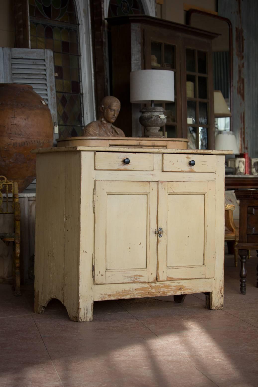 Antique pine two-door and two-drawer cupboard with original butter color paint from Alsace, France.