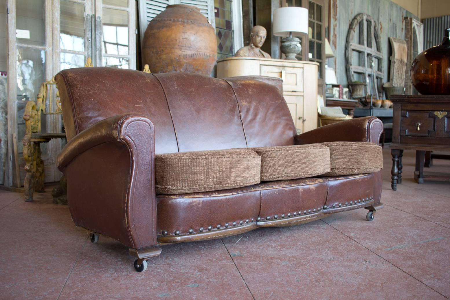 Vintage 1950s French Odeon style leather settee with triple bow front and flare back.