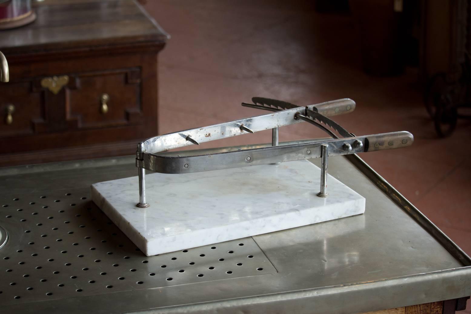 Lovely antique French jambon/ham holder on white Carrara marble base and wood handle grips. The steel mechanism with adjustable sharp spiked jaws holds the ham in place.