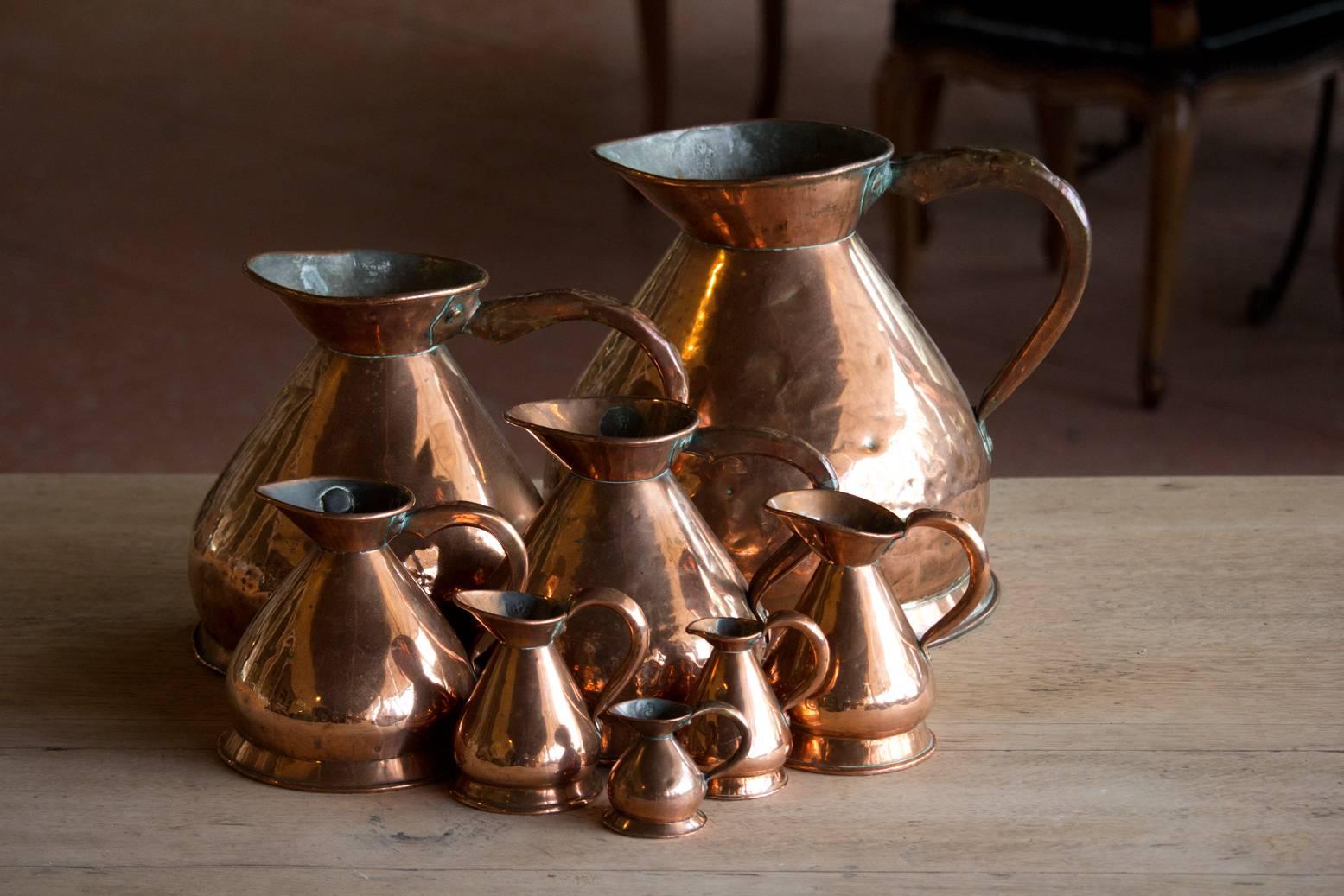 Antique set of eight copper Haystack measuring jugs, graduated in size. Each one has its British weights and measures lead seal applied by the official who would inspect them to make sure the publican was not cheating on the quantity. It would