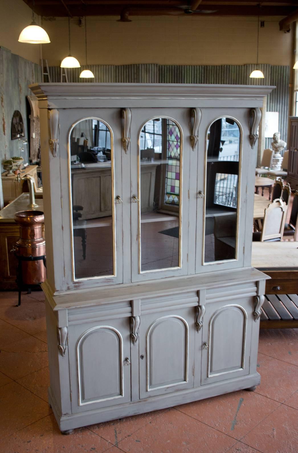 Antique English bookcase or library cupboard. It has three long arched glazed doors over three solid raised arched paneled doors and drawers. I has eight beautiful carved corbels. Would look great in a kitchen with plenty of room for crockery,