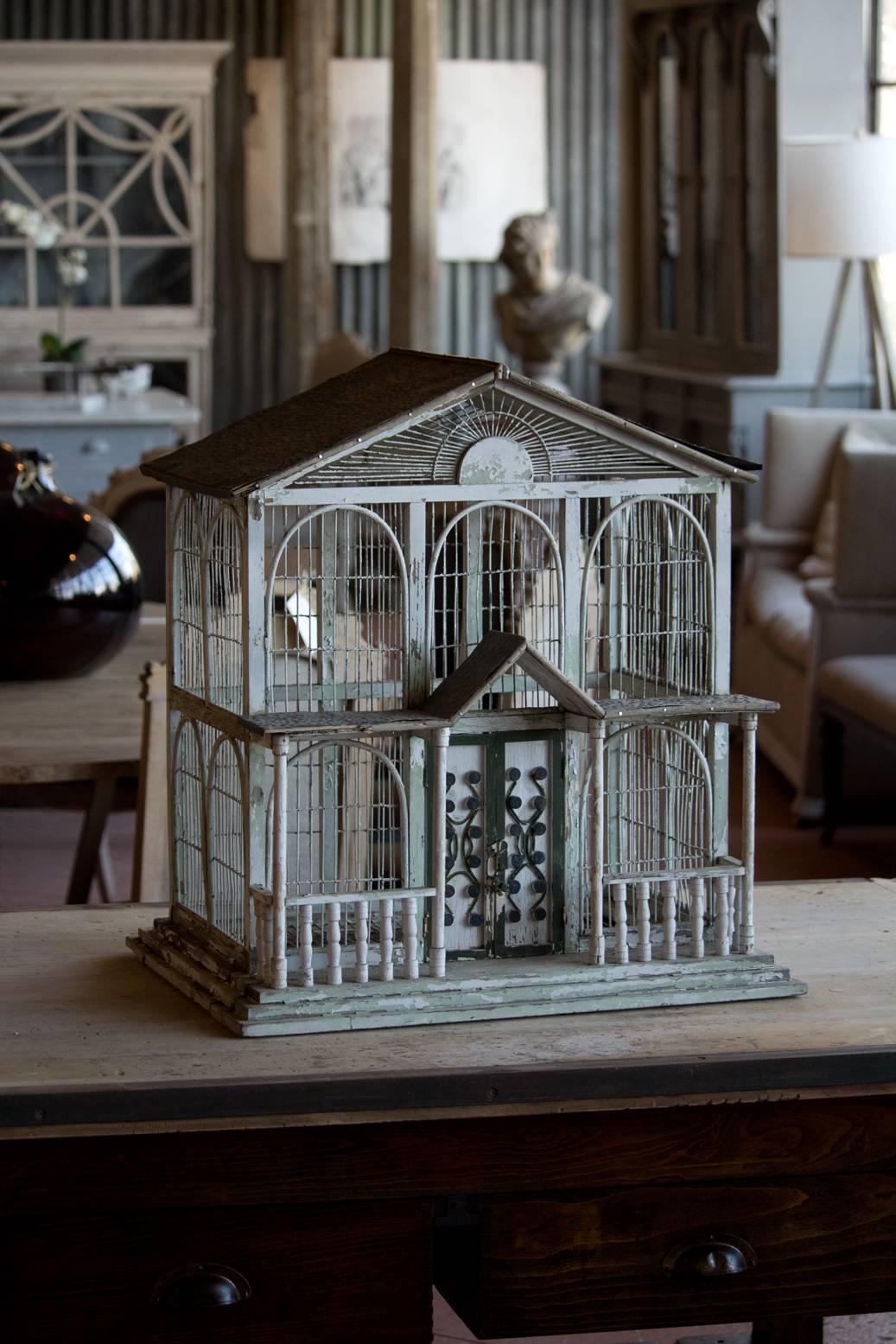 Folksy American vintage bird cage in the Gothic Revival style with porch and decorative door. It has lots of character and chippy paint.
