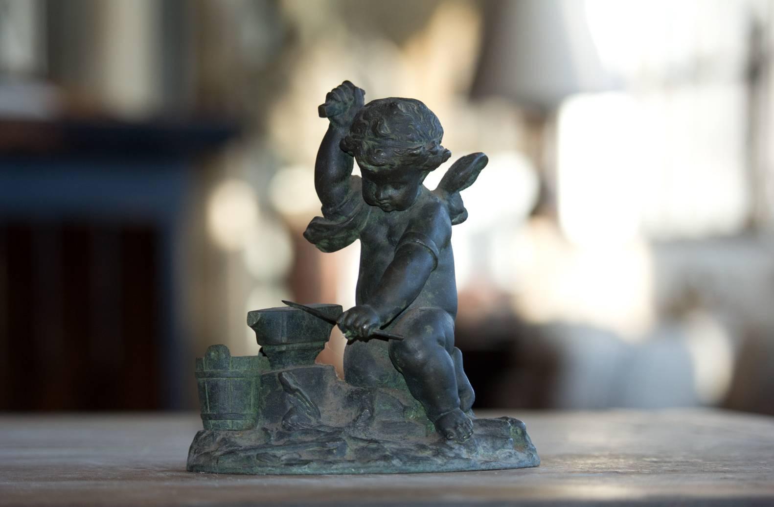 Antique bronze of cupid sharpening his arrow. Lots of lovely detail showing the anvil, pail and arrow on the ground. Beautiful patina.