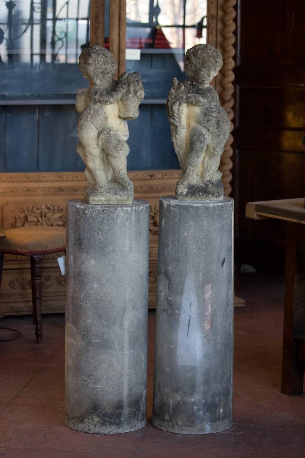 Pair of vintage cast stone putti on tall columns. One representing summer and the other fall.

Beautiful patina and a wonderful addition to a country garden!