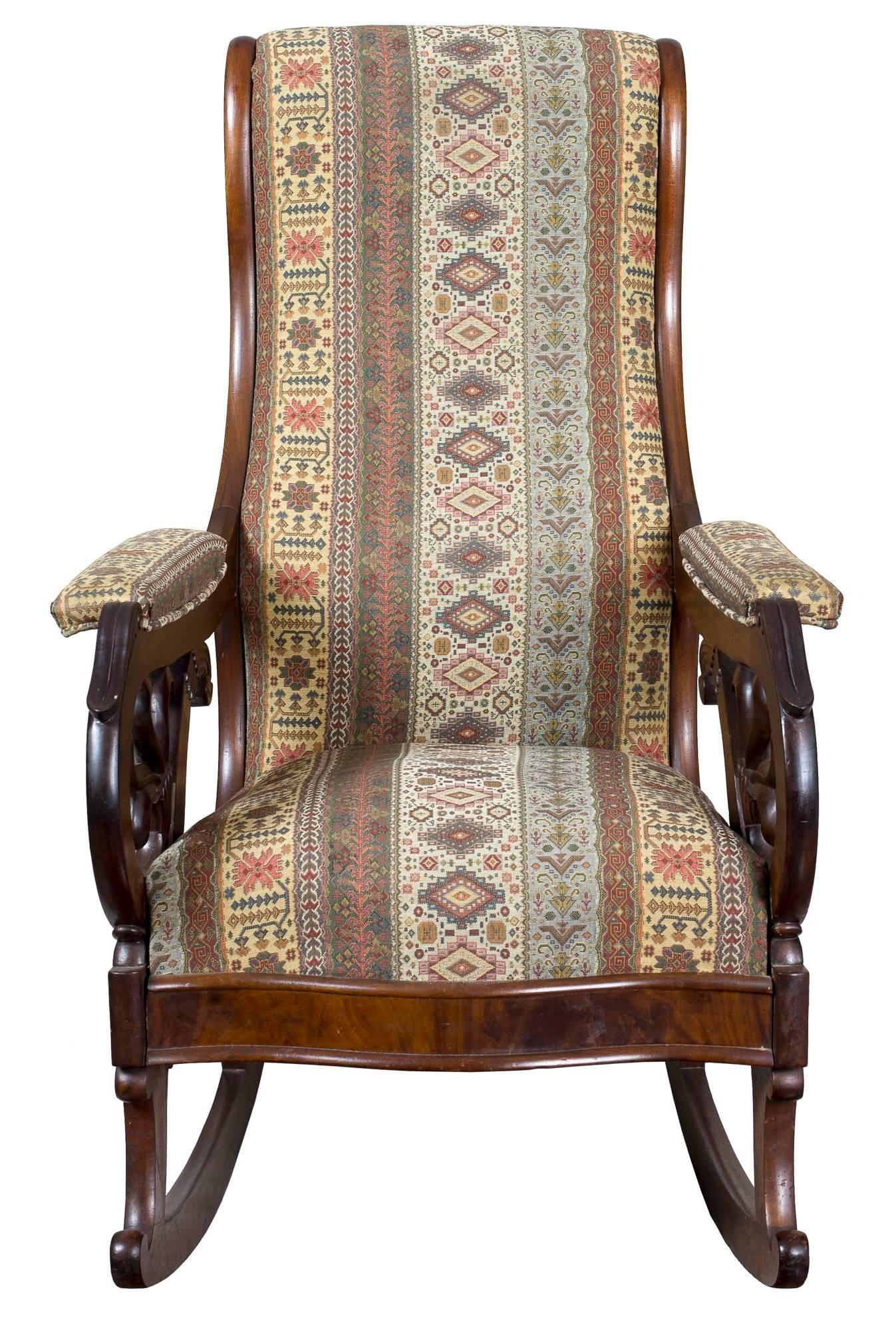 This rocker is quite substantial, with beautifully carved scrolled arms with lambs’ tongue detail at the top. It is in fine condition with springs and good upholstery. This very comfortable rocker, which moves away from the country idiom toward the