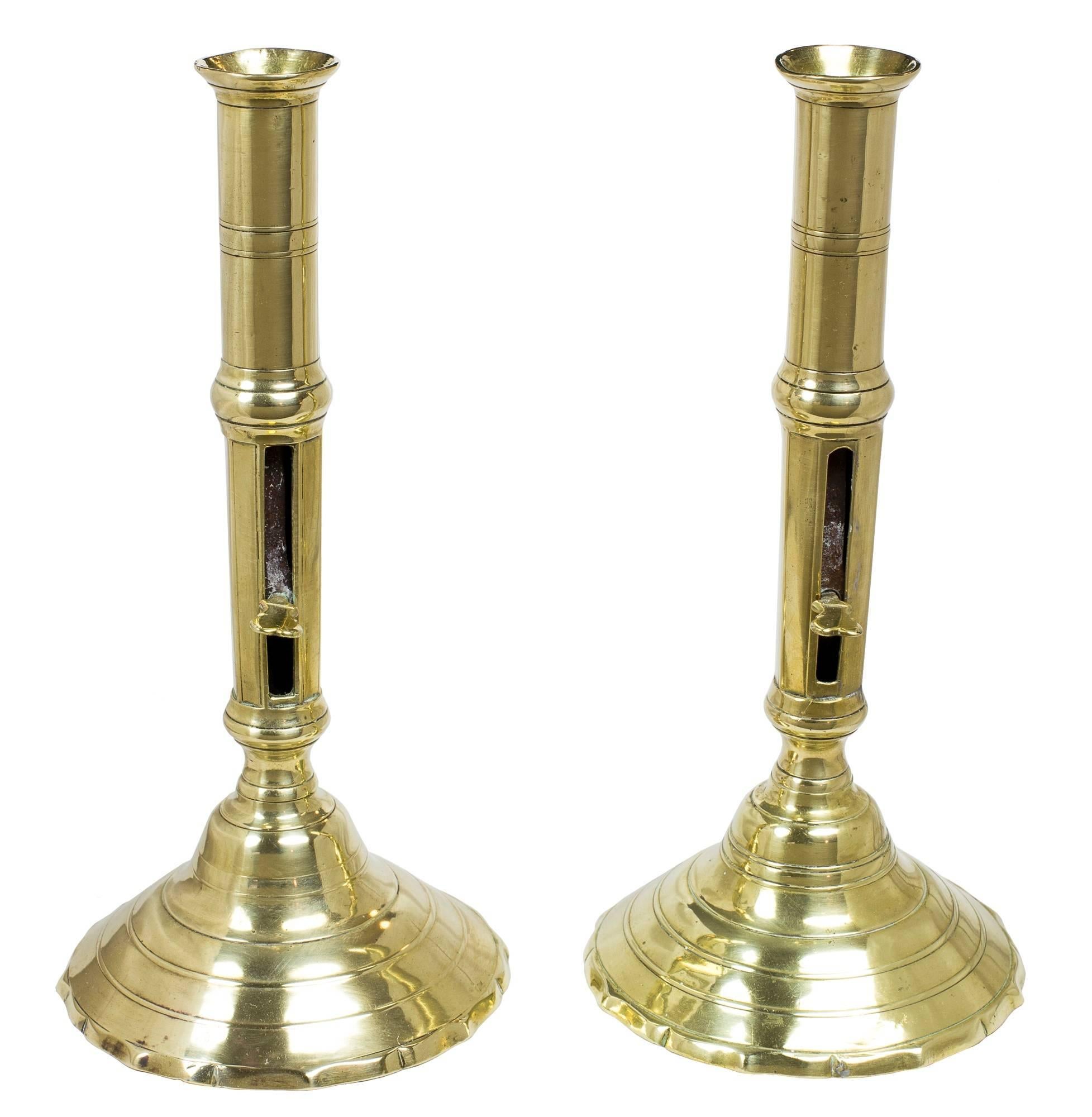 A pair of French push-up brass candlesticks, with circular stepped base, circa 1750-1780.