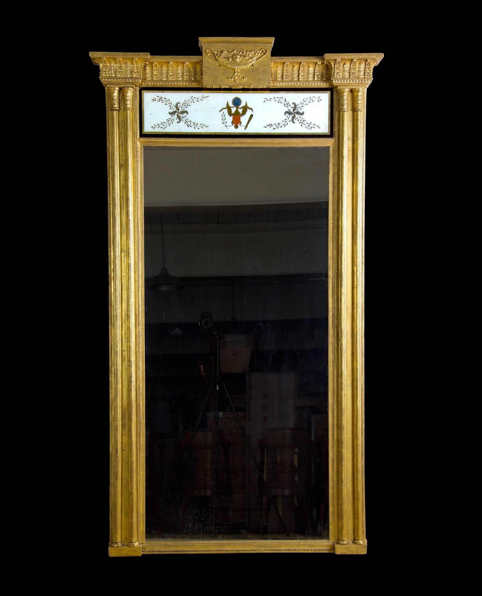 This is an important églomisé pier mirror with giltwood frame. The large-scale and dramatic proportions of this mirror are enhanced by a Fine églomisé glass panel in the frieze depicting an American Eagle clutching a banner reading 