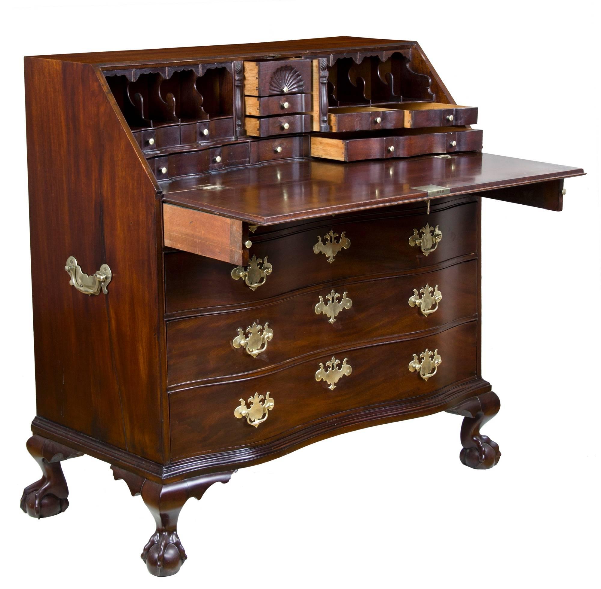 This desk is composed of dark purple Cuban mahogany and is quite heavy. Its drawers are oxbow in form and are molded from solid mahogany logs. The desk is supported by four magnificently carved claw and ball feet and lend a heft to its countenance.