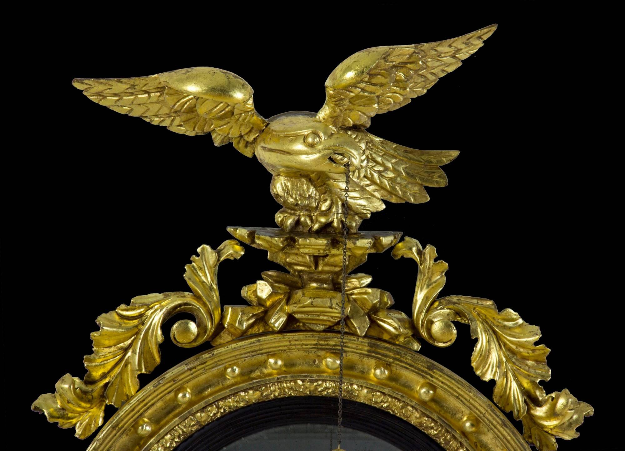 This is a moderately sized girandole retaining all its original parts. The mirror shows beautiful oxidation and a gilt in excellent condition. The eagle is beautifully carved, holding a ball and is a Classic of its type. The leafage is beautifully