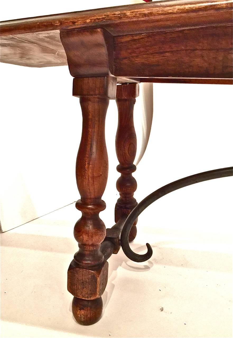 Pair of Spanish Revival solid walnut and forged iron trestle benches. The benches were created, circa 1920-1930 in a Baroque or Renaissance style. Both benches are in excellent original condition; they could be joined to a Spanish Revival table,