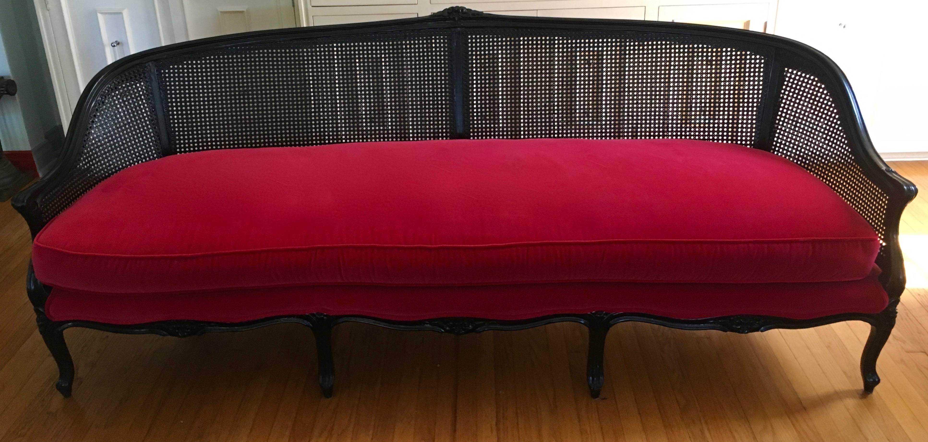 Early 20th century cane back sofa. Pillows and cushions are upholstered in Red Belgian velvet - each pillow has a bouclé fabric in a light pink / red alternate back.

The cushions and pillows are independent of the sofa - easy to re-upholster if