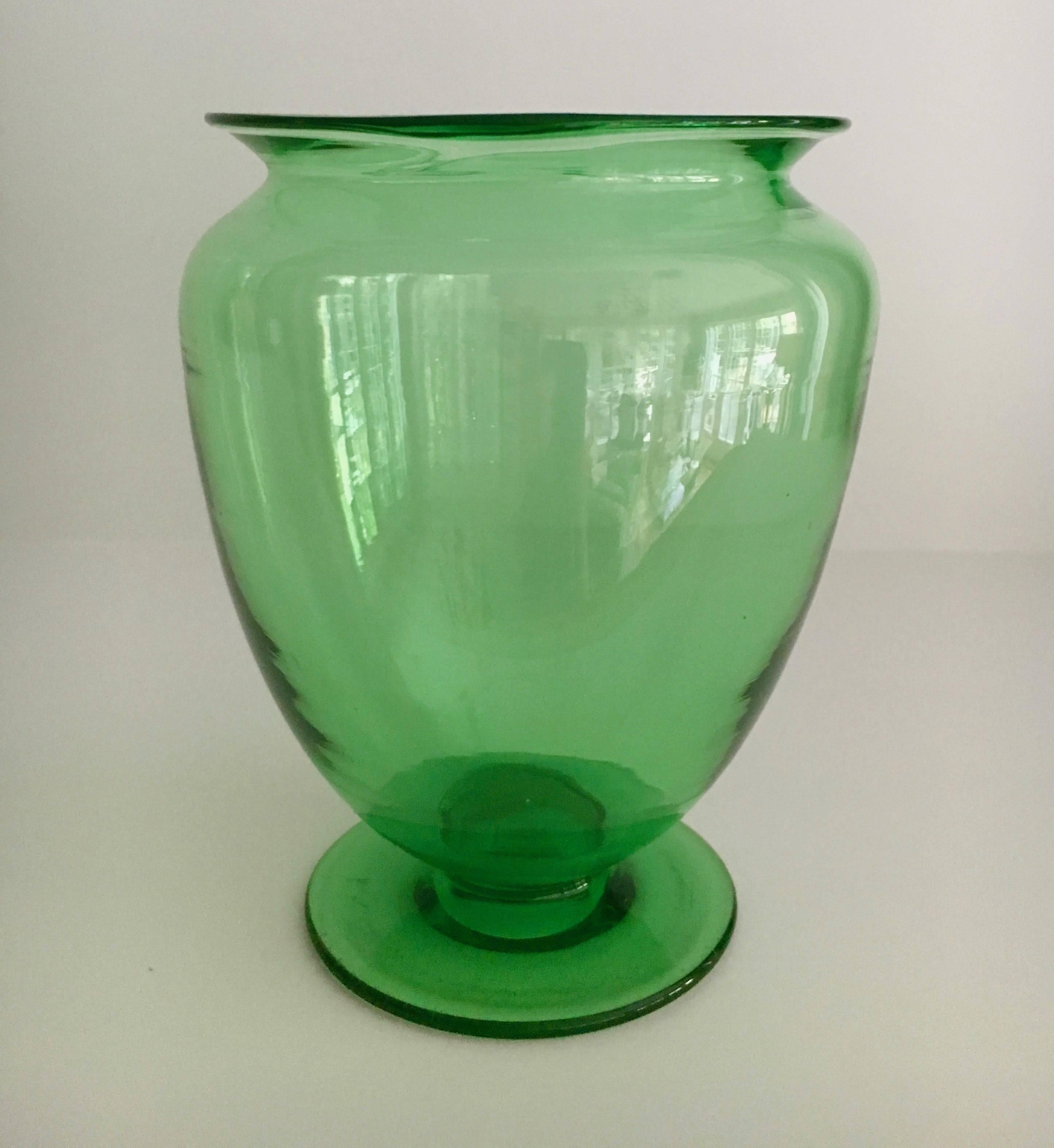 The green glass, shape and style of this piece are undoubtedly derived or borrowed from Steuben.  The vase is of quality and makes a handsome addition to any desk, bedside, guest room or small statement of flowers.