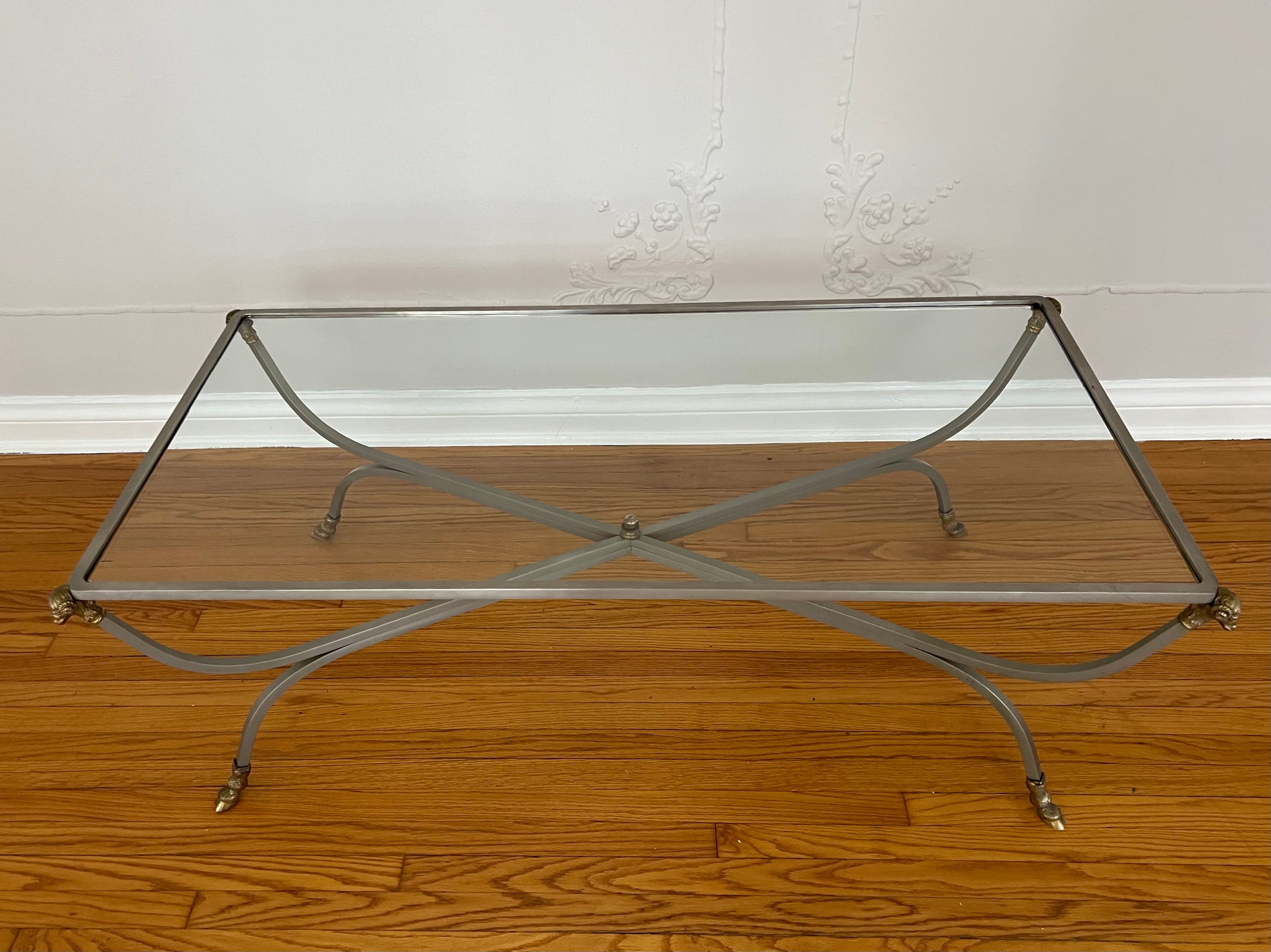 In the style of Maison Jansen, the Cocktail table is supported by four brass rams heads with hoof feet. A wonderful mid century piece and perfectly suited for many room. the glass does have a few irregularities - the pieces details are solid brass