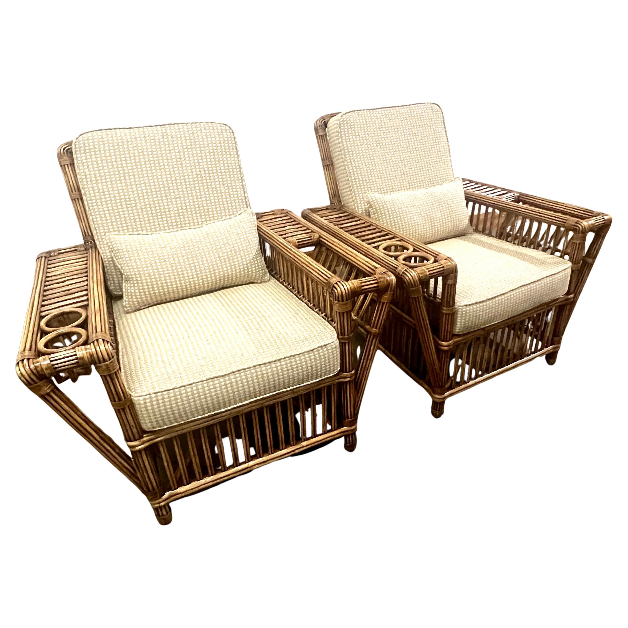 A terrific Pair of Stick Rattan Chairs in the Style of Art Deco.  The pair are in beautiful condition with the rattan refinished.  Each chair is very deep and comfy with a lumbar pillow.   A nice addition to the chairs are cup holders and magazine