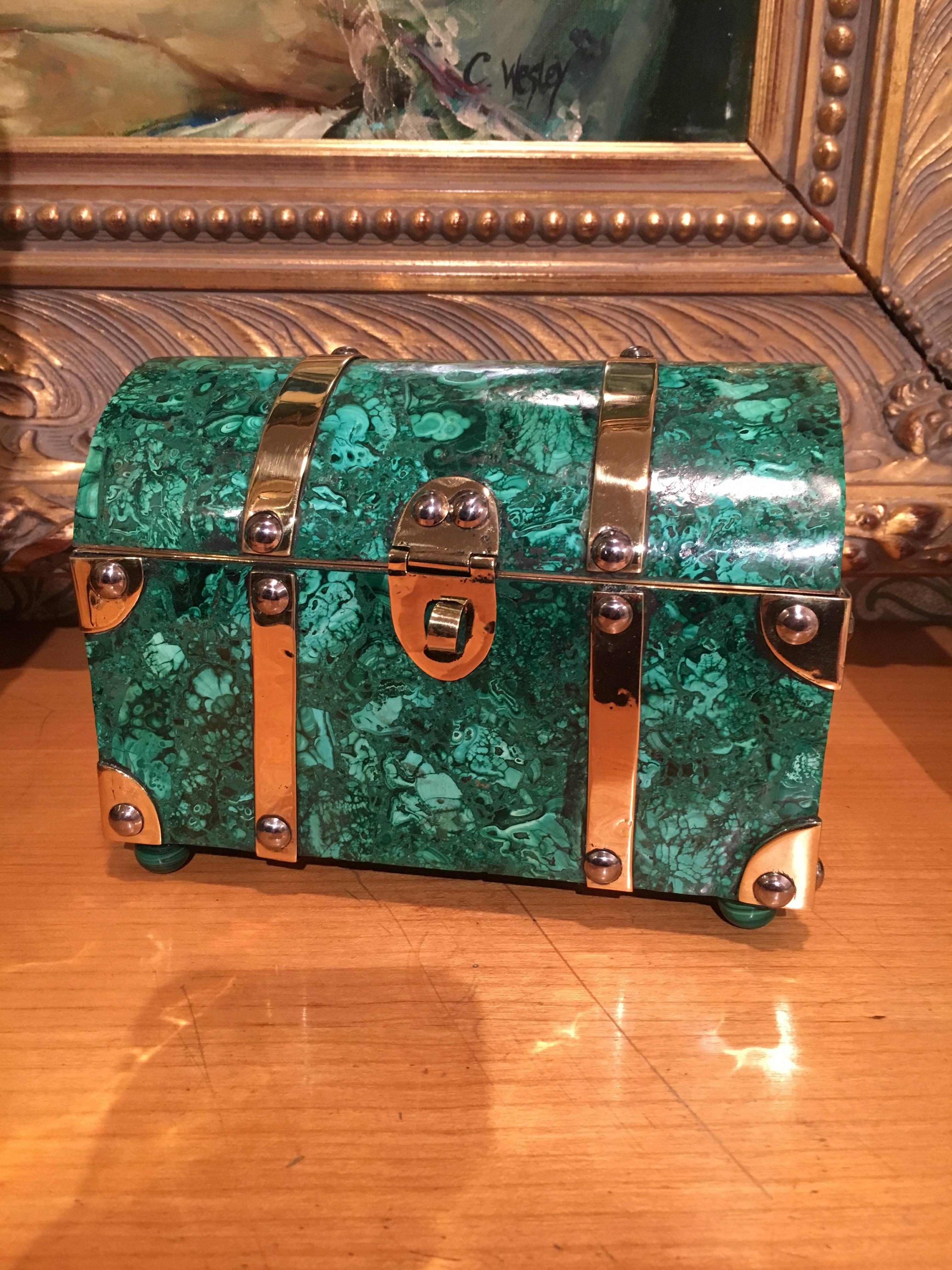 Superb Malachite box trimmed in brass, in the shape of a treasure chest. The piece rests on four ball feet in Malachite.

Befitting of the office, den or study  the box is large enough to hold love letters and small enough to store jewelry and