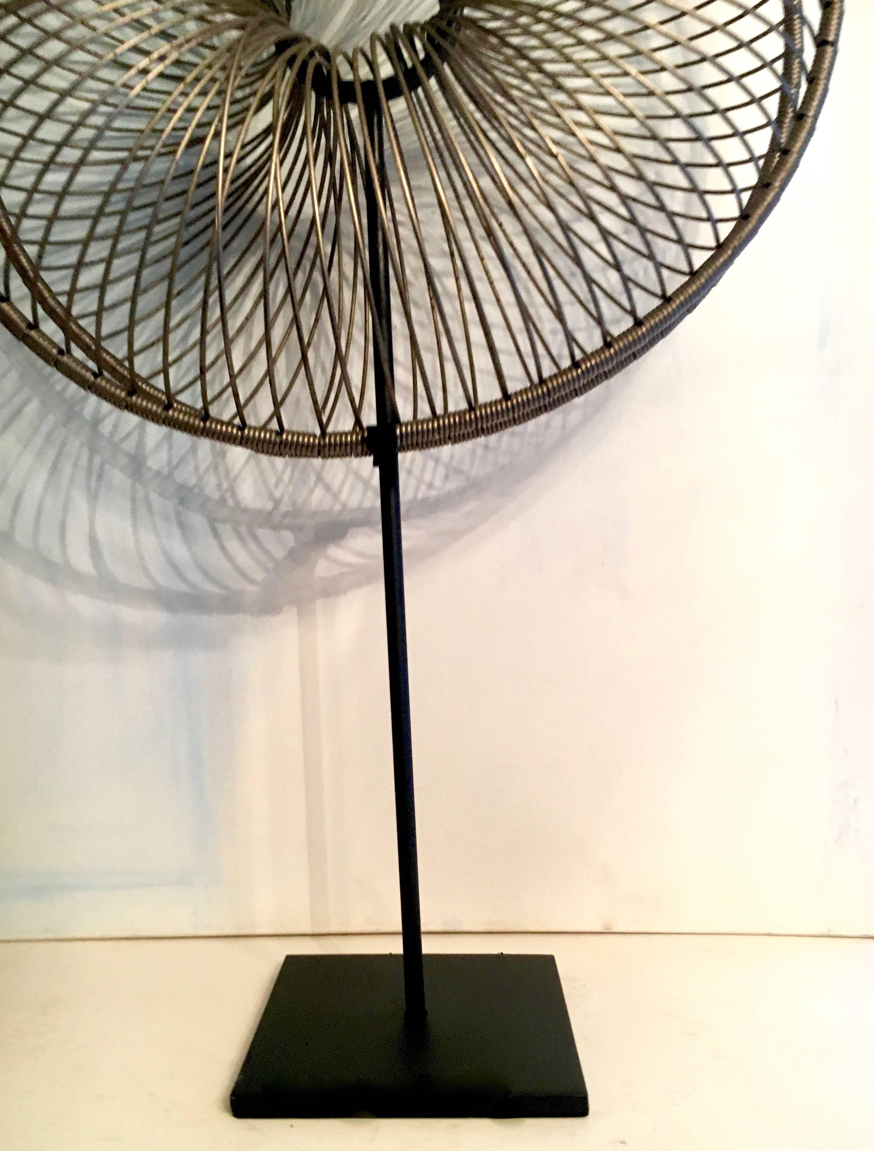 A very unique and interesting wire sculpture - what looks to be a form for a tire or large metal donut, is not found art. It's art and we found it!

The black iron base was custom built for the piece an now can sit proudly on any large shelf,