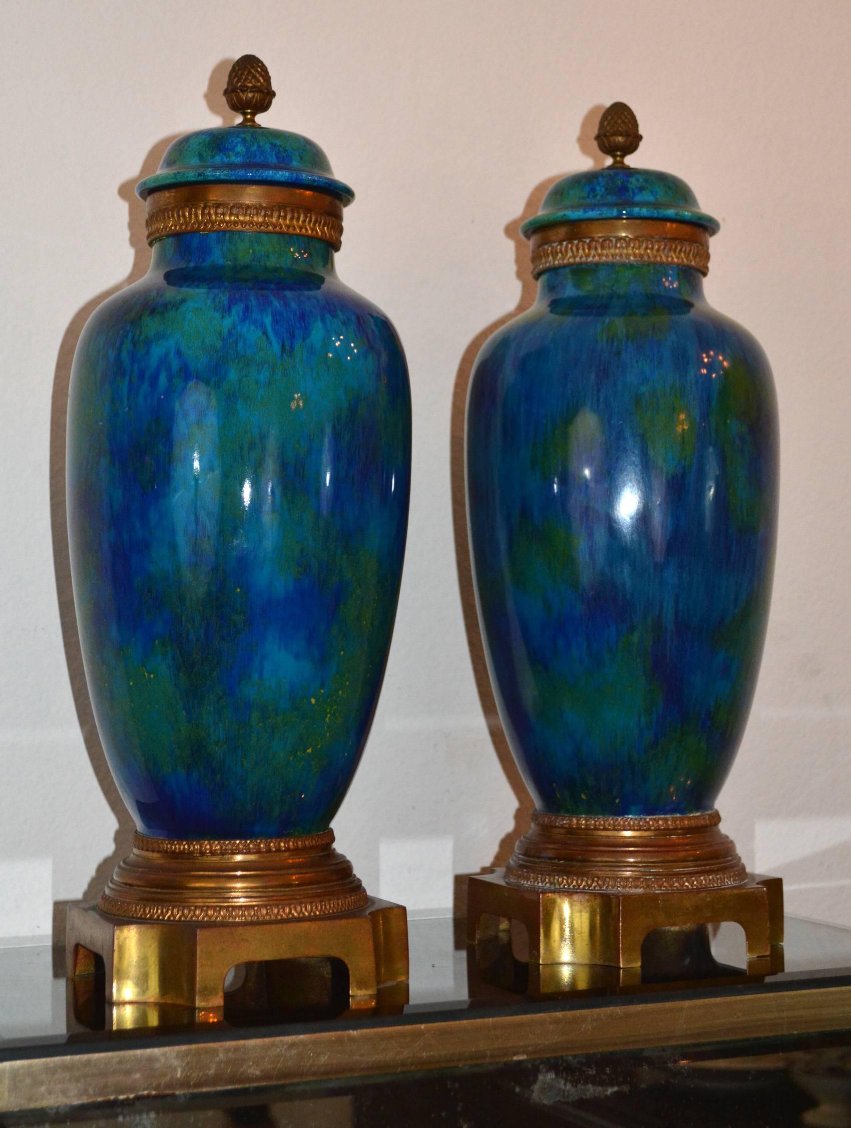 Paire de vases Art Déco de forme balustre avec couvercles. Une belle glaçure dans différents tons de bleu, aqua, vert et or. Le vase repose sur des pieds en bronze doré et est marqué C.H. Sèvres. Ces vases sont un exemple rare et très fin de l'Art