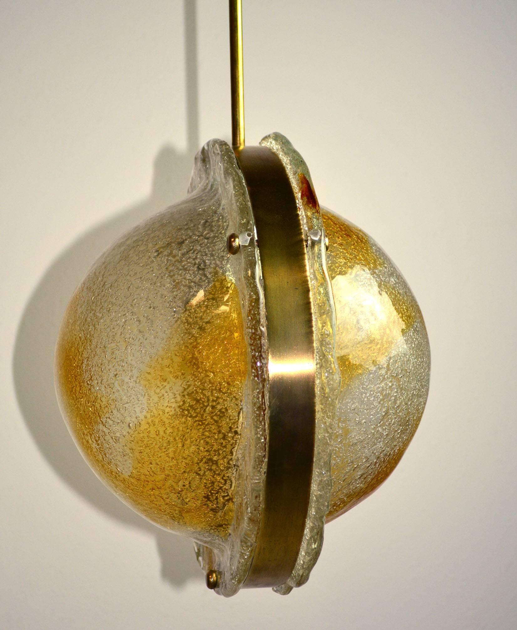 An Italian Murano glass light fixture by Mazzega of two cast pieces of clear glass with amber swirls on a brass tone armature.