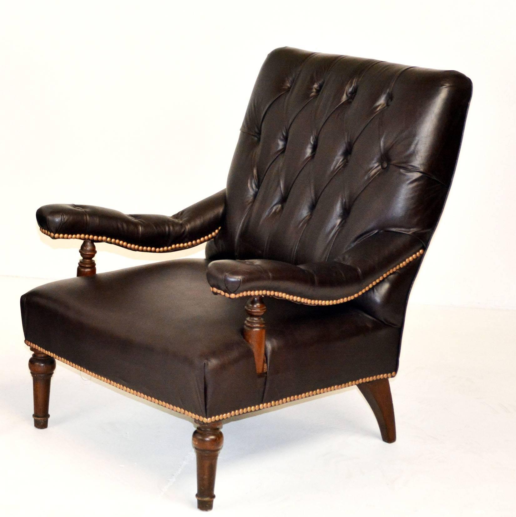 A pair of Edwardian leather upholstered armchairs with square back and open arms, all raised on all balustrade legs. Reupholstered within the past ten years in chocolate leather with shallow button tufting and brass nailheads. Referred to as lolling