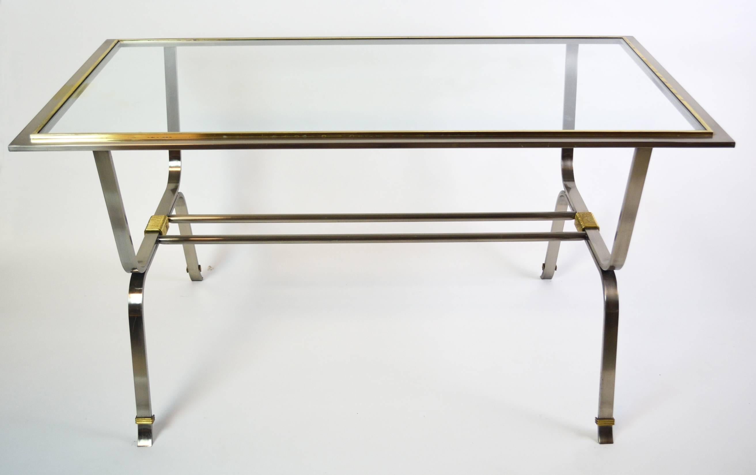 Mid-Century Modern table of stainless steel with brass accents and inset glass top. In the style of Ramsay or Maison Jansen nut not documented. Wear to brass on top gallery as per photos. Exceptional style.