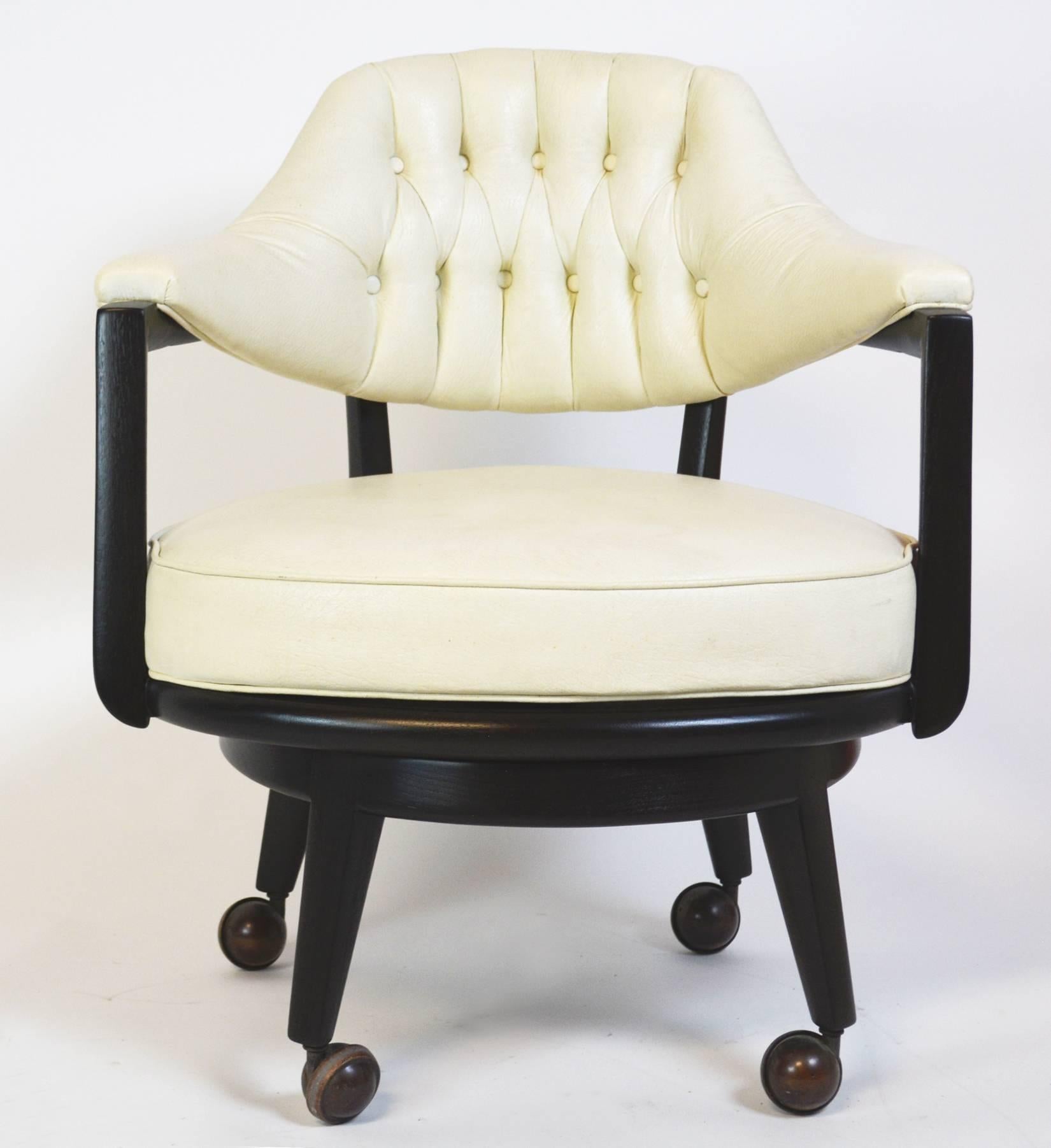 A fantastic pair of Monteverdi-Young swivel chairs designed by Maurice Bailey. Refinished, ebonized wood frame and base with original castors. Original upholstery and button tufted white leatherette in good condition, with age appropriate wear and