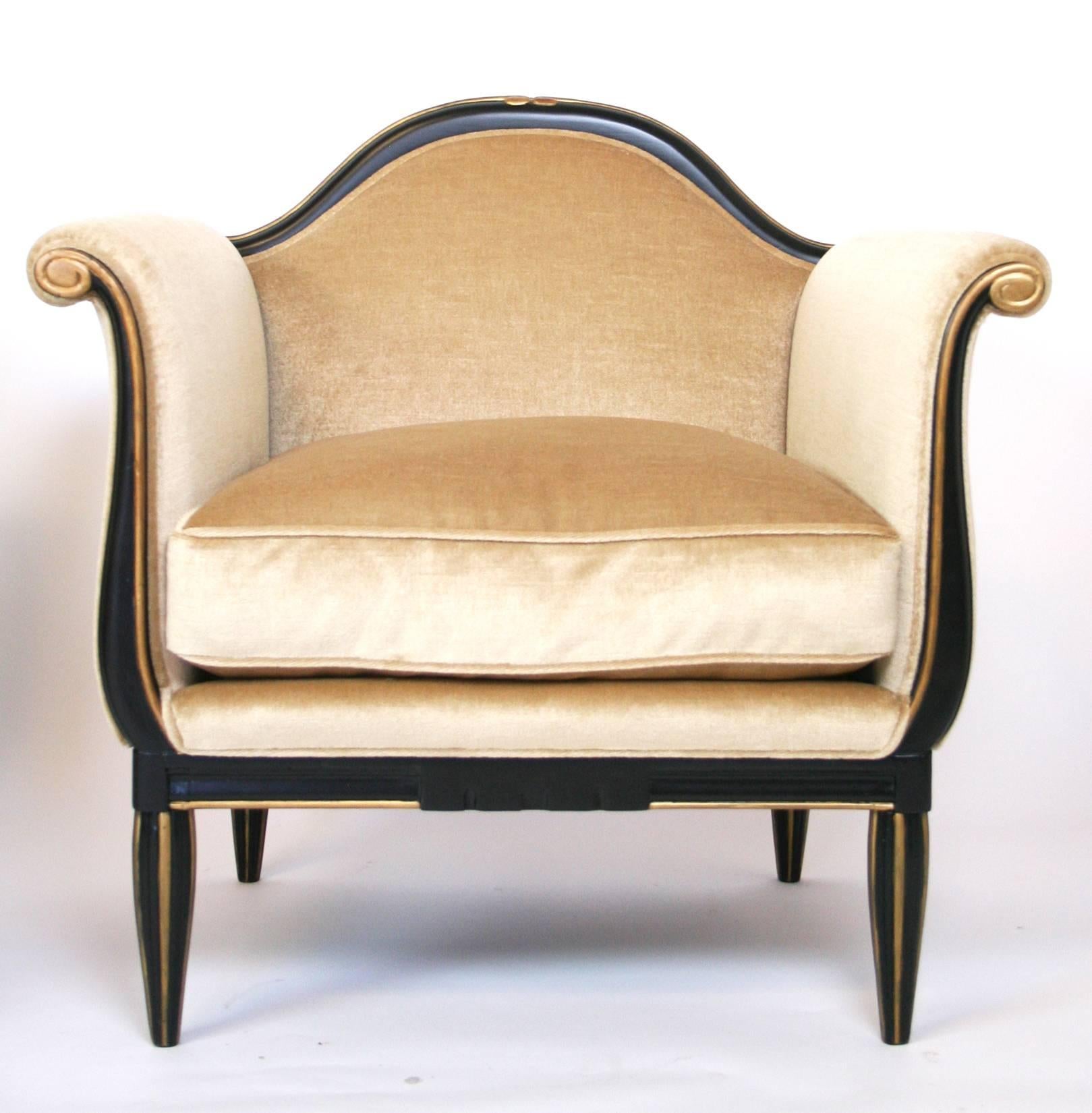 A pair of French Art Deco lounge chairs in the manner of Paul Follot. Black lacquered and gold carved, fluted legs and frame. Newly upholstered.