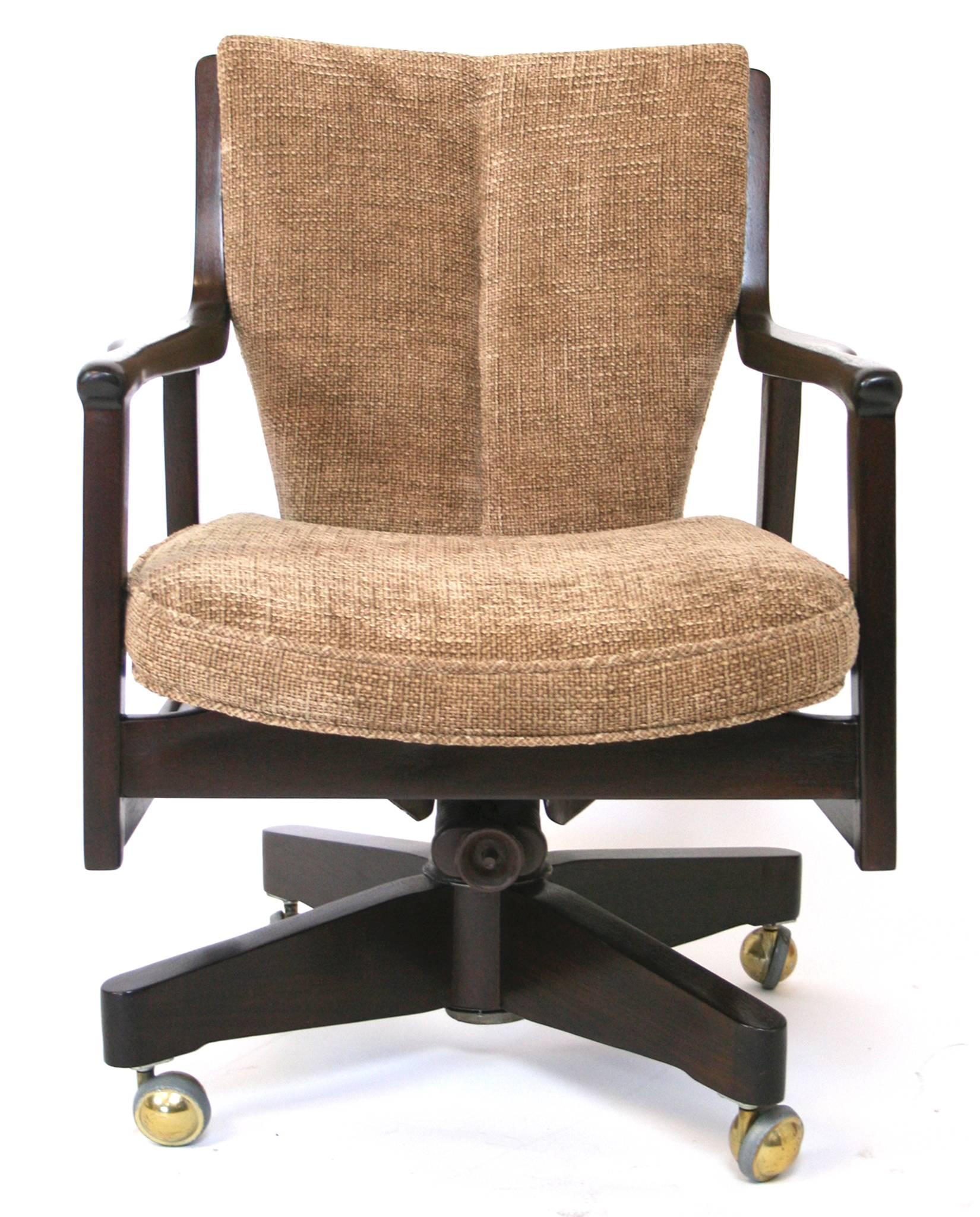 A swivel, adjusting desk chair in walnut with new upholstery. Shaped arms with tapered, channeled back.