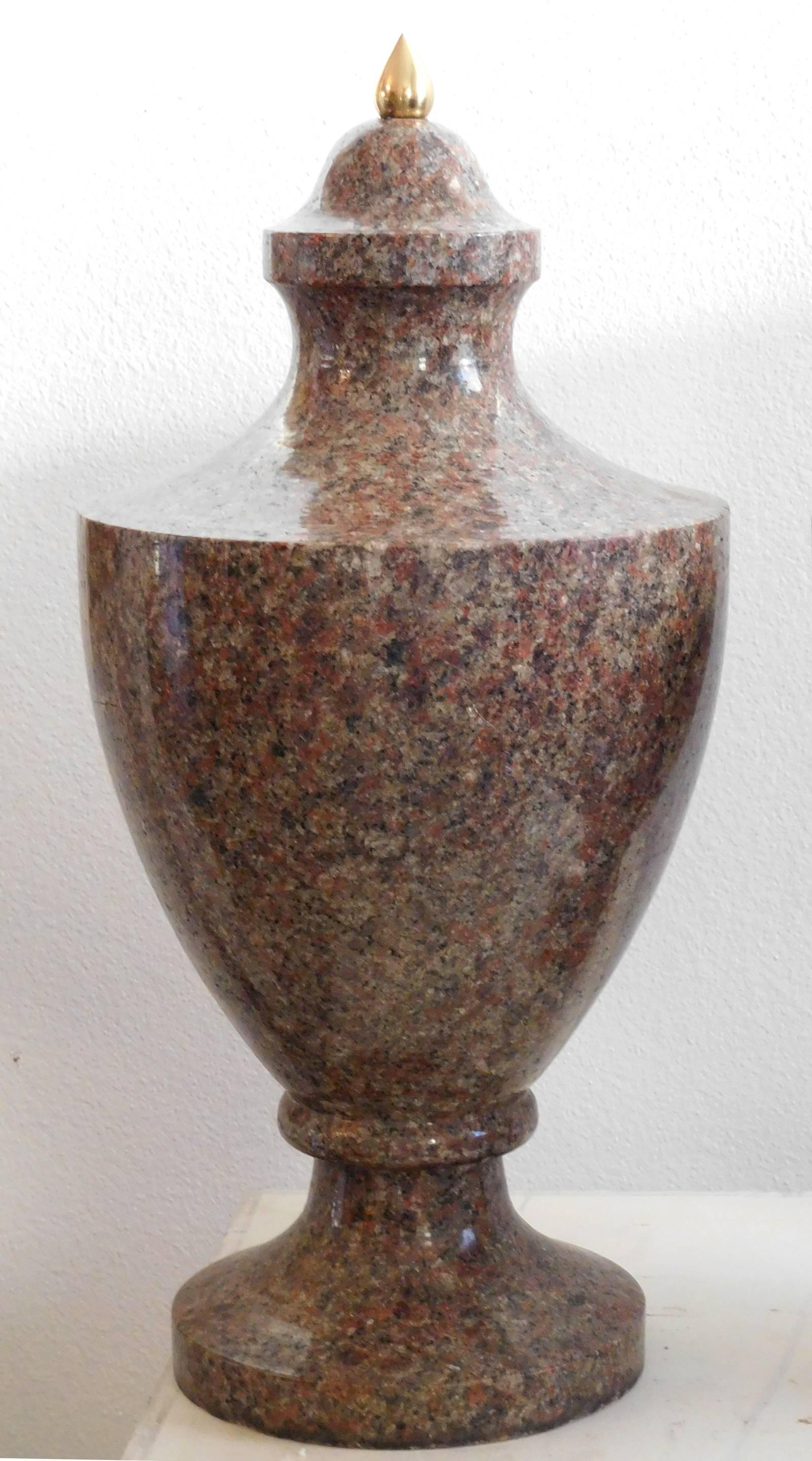 18th-19th century, each urn formed from a solid block of reddish, grey and black stone and of typical lidded form, granite, 24 in., generally good condition, scattered minor base chips, top of each with slight discoloration under new brass finial.