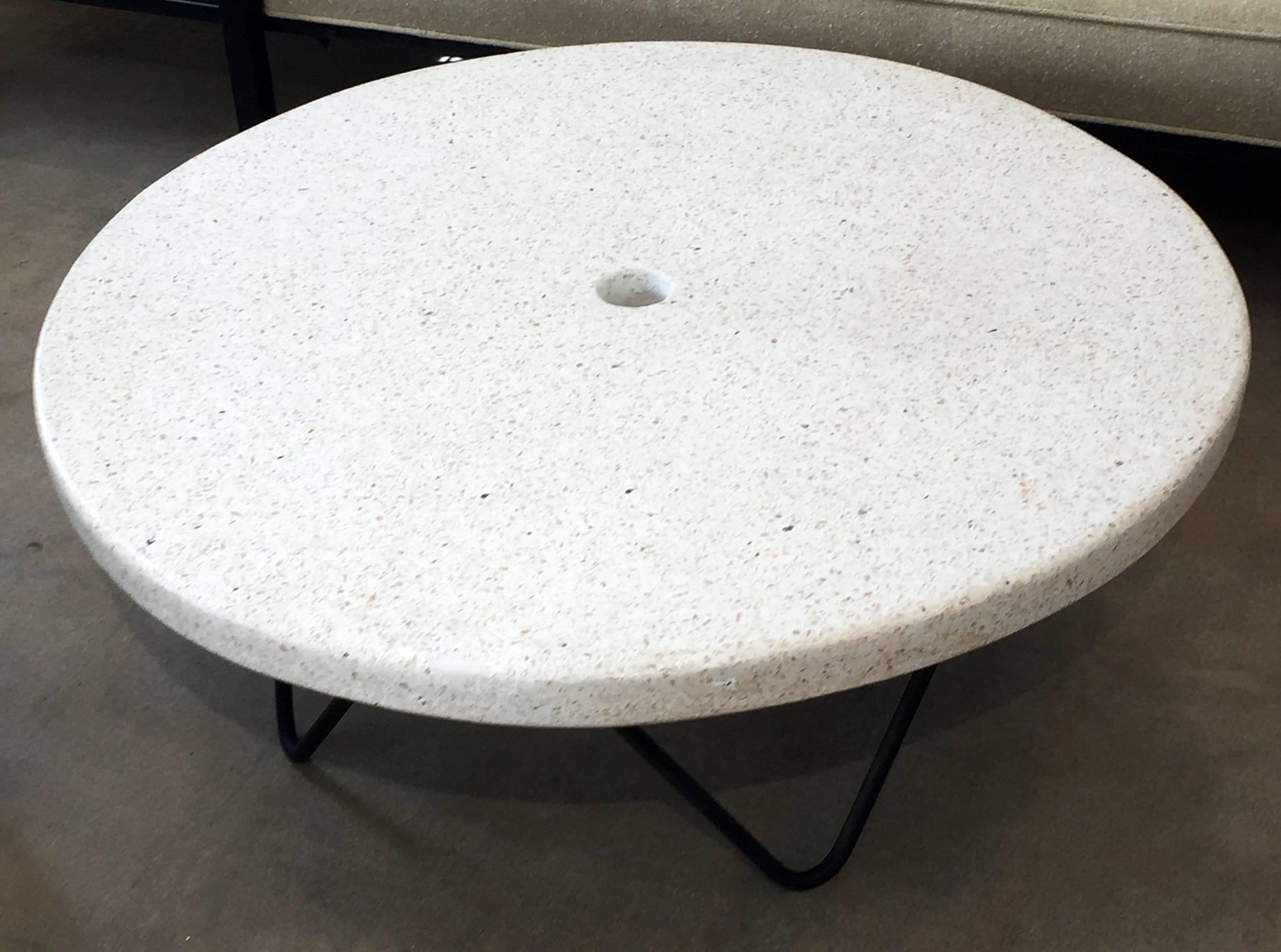 A custom Mid-Century Modern coffee table for exterior use. 2" thick poured terrazzo top with bent wrought iron rod base in the style of William "Billy" Haines. Top has a 2" diameter hole for an umbrella. We can provide a brass