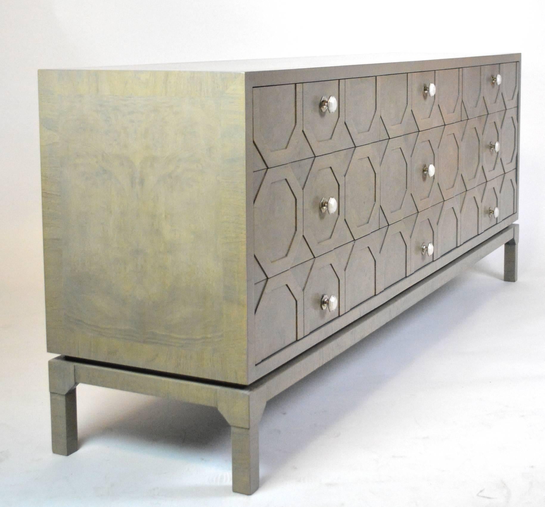A rare nine-drawer dresser with octagonal lattice relief detail on the drawer fronts. The upper case floats on a separate base. Burled wood refinished in a silver gray stain.