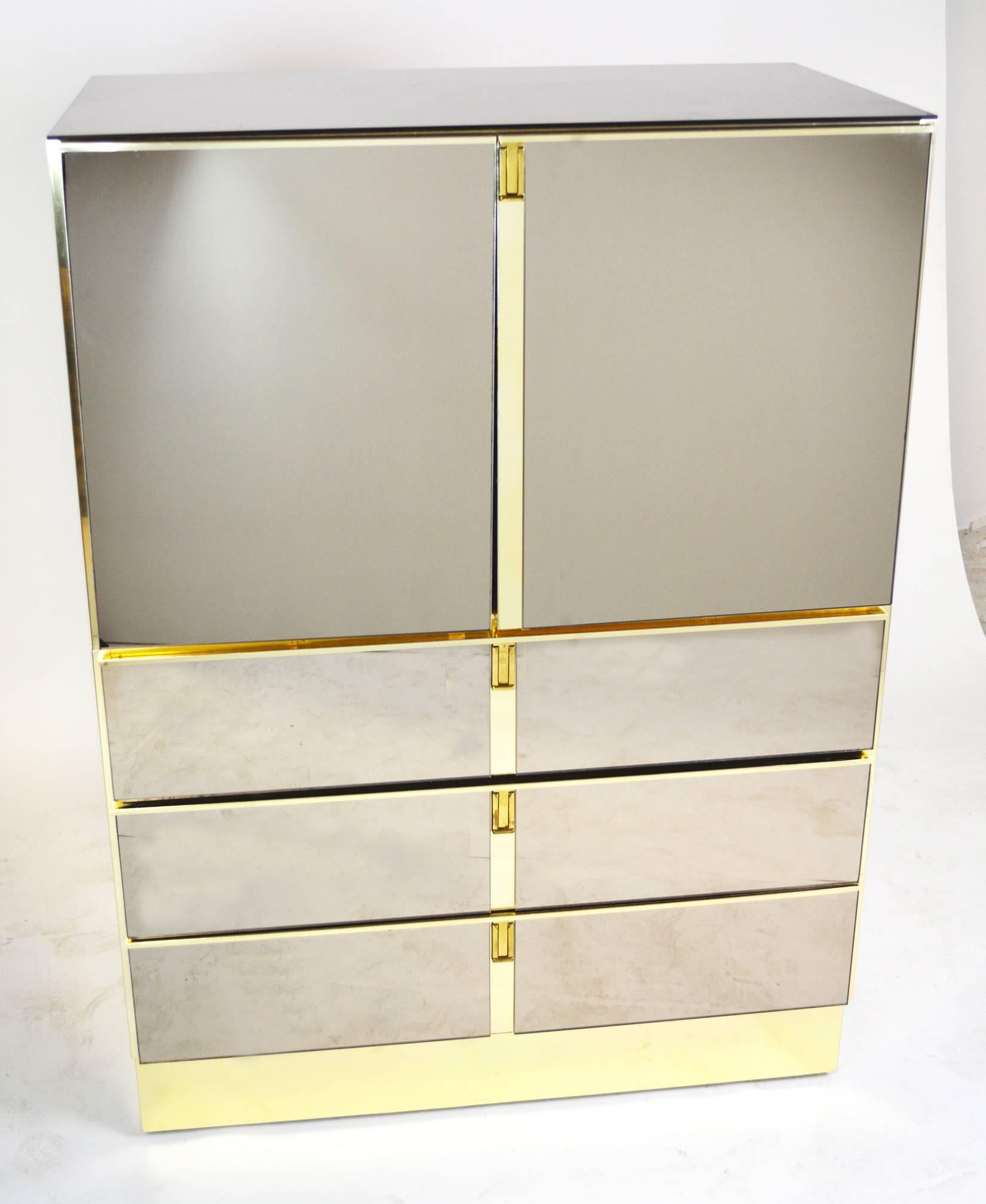 A two-part mirrored cabinet on chest, perfect for a bar. Two mirrored doors above three mirrored drawers with modern inset brass campaign handles, on a brass base with brass sides. Glass is perfect with a few minor scratches typical of usual wear.