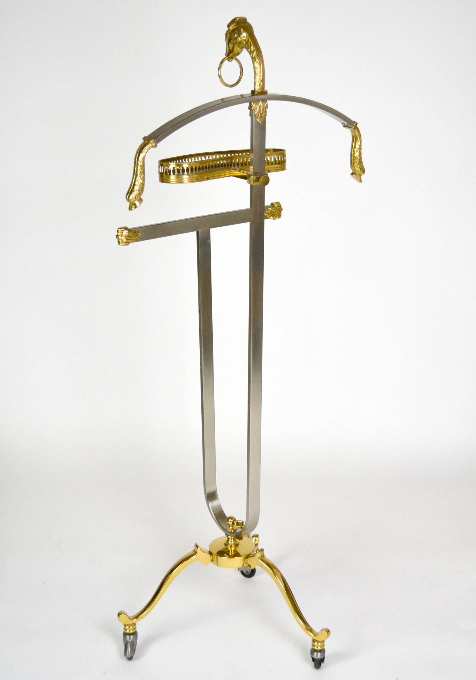A beautiful Italian steel and brass valet with cast ram's heads with ring and hooves accents. Adjustable leatherette lined jewelry tray and a tripod base with brass caster wheels. The base measures at 15 1/2" in diameter. Marked 'Made in