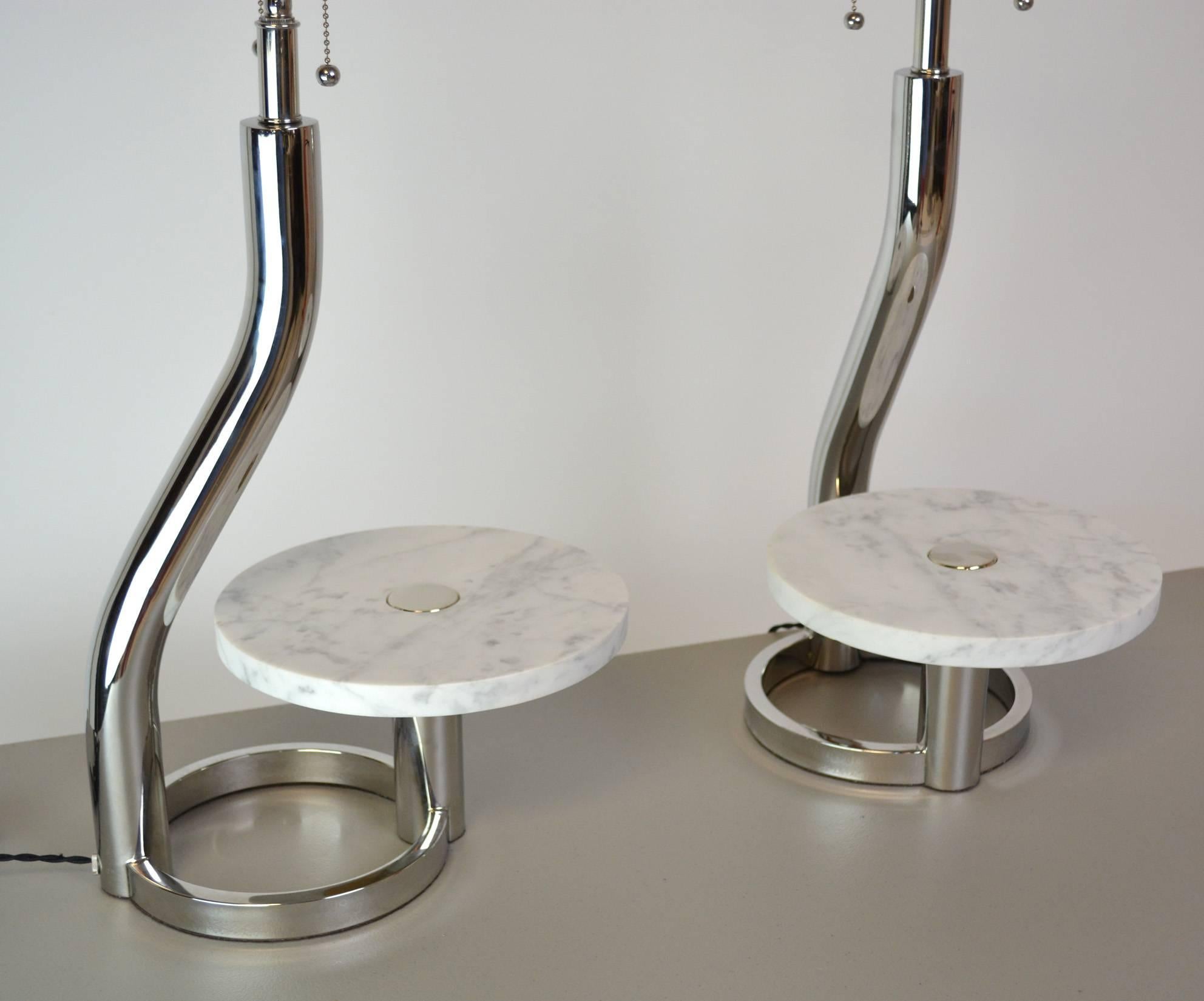 A chic pair of chrome lamps with marble discs that can be used to display objects. Rewired with new double cluster sockets and French braid cloth cord. Shades for display only.