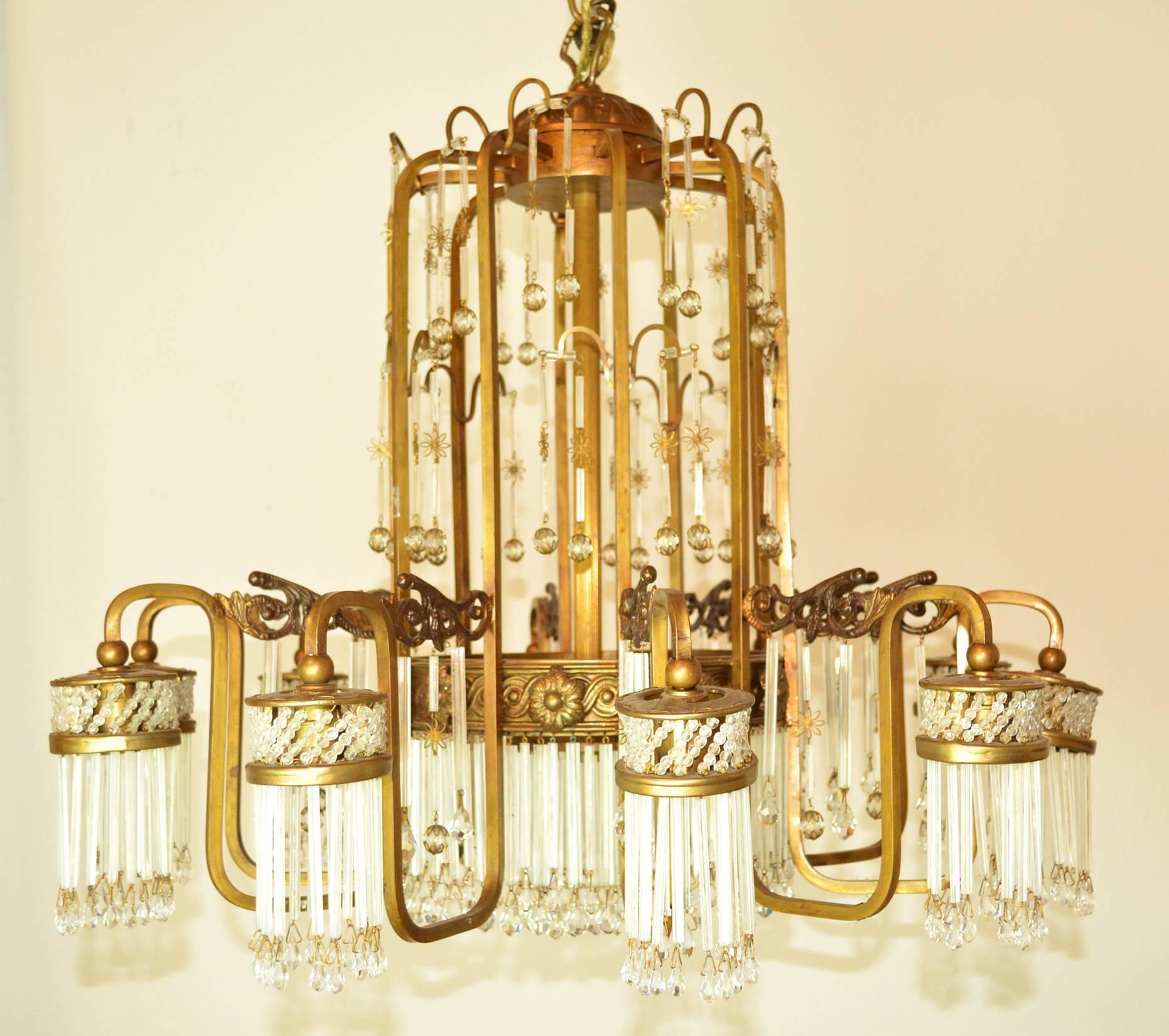An Art Deco chandelier with a gold tone metal frame with cascading glass rods and beads. Ten lights, each surrounded by glass rods.
