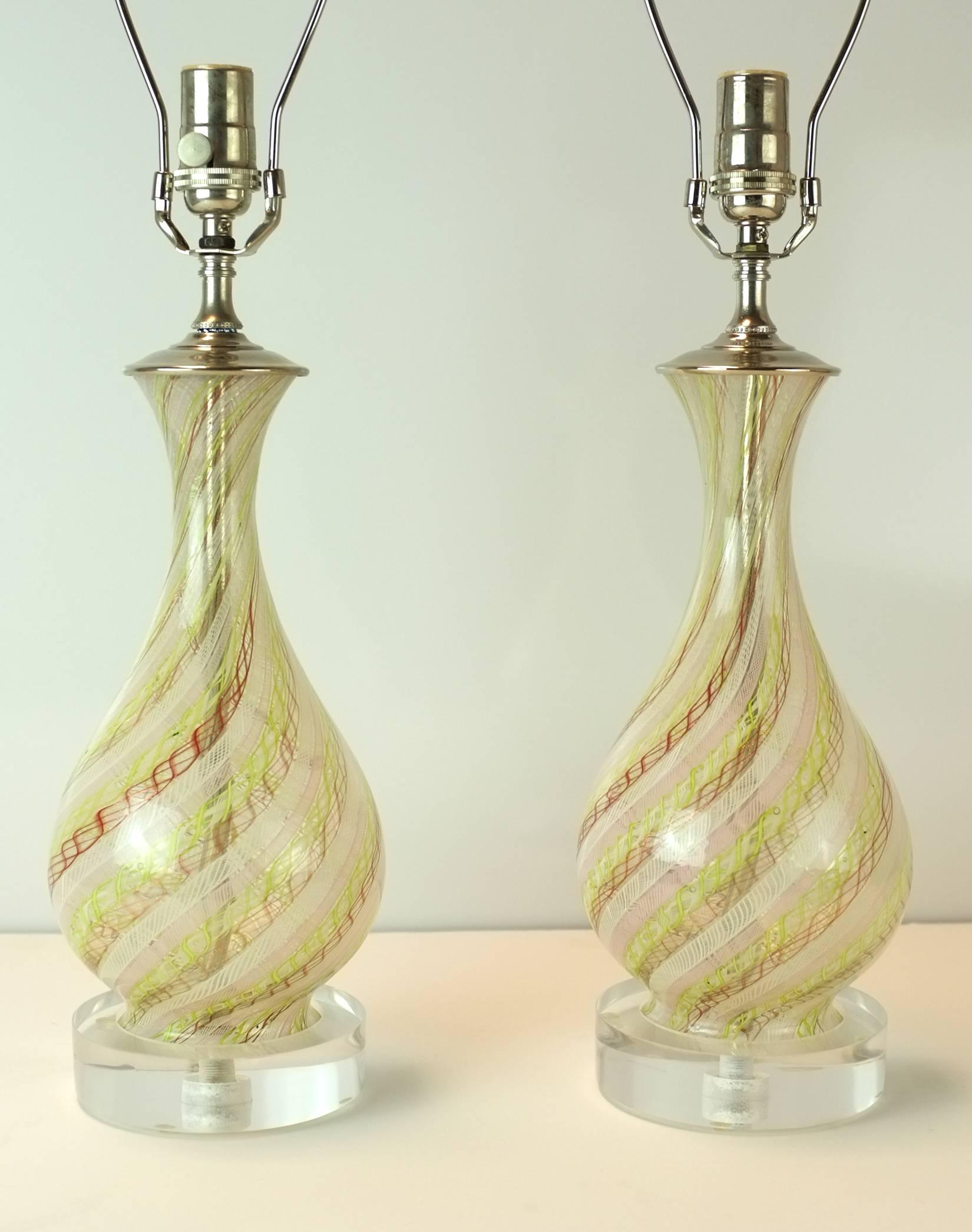 A good pair of Italian Mid-Century Mezza Filigrana Murrain glass lamps attributed to Dino Martens for Areliano Tosso.   Each baluster form swirls with citron, white, gold and bronze stripes.  The hardware is a crisp and shiny chrome and they are