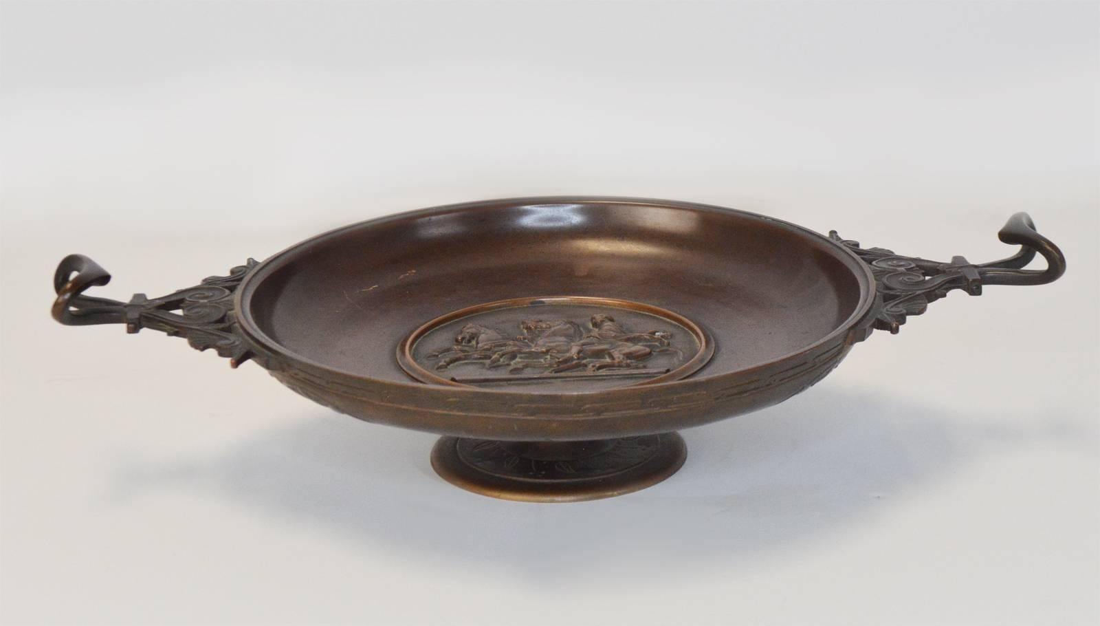 A good 19th century Italian bronze neo-greque footed Tazza with scrolled handles and arge, round centrepiece, in the centre with a round relief medallion with an antique classical scene. The two handles with cast Bacchus heads. Ferdinand Levillain