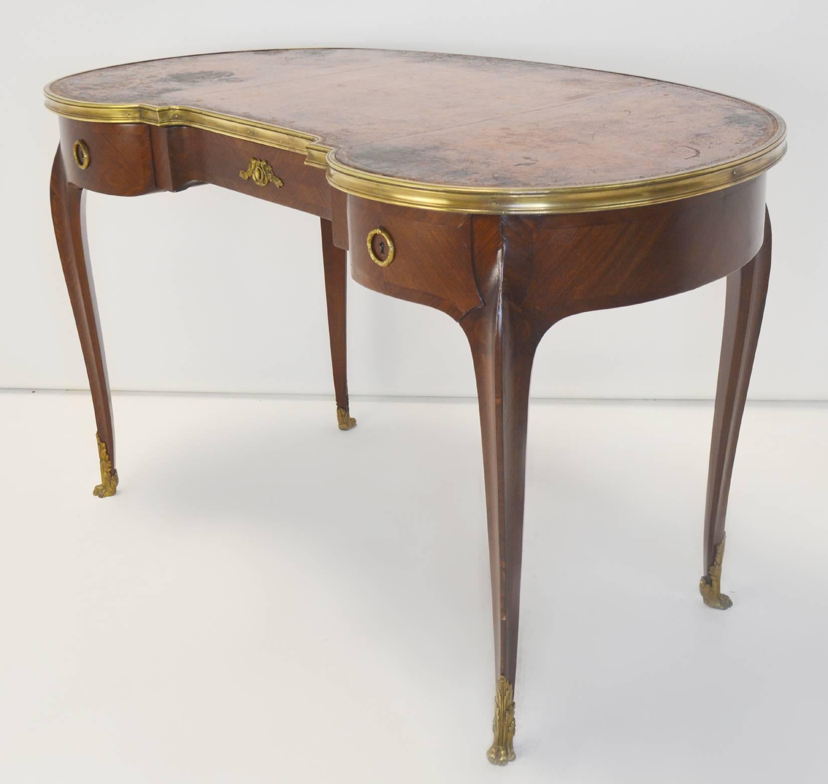 A good quality late 19th-early 20th century Louis XV style writing table with original embossed leather top with gilt bronze surround and mounts. Lovely parquetry work to the veneers. Patina to leather top as shown.