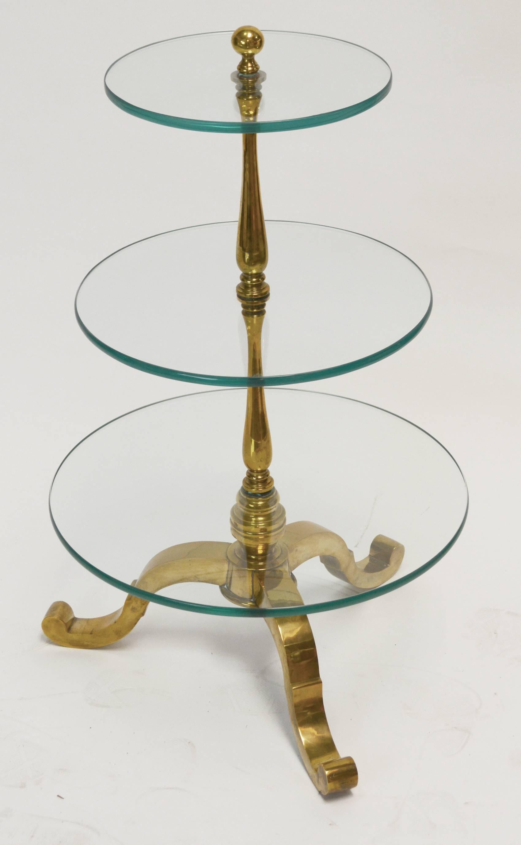 Dumbwaiter in the form of a Georgian three-tier dumbwaiter, with turned central column and tripod base in solid brass, with three thick glass shelves. A very elegant example of the form. Unmarked, but most likely Italian.