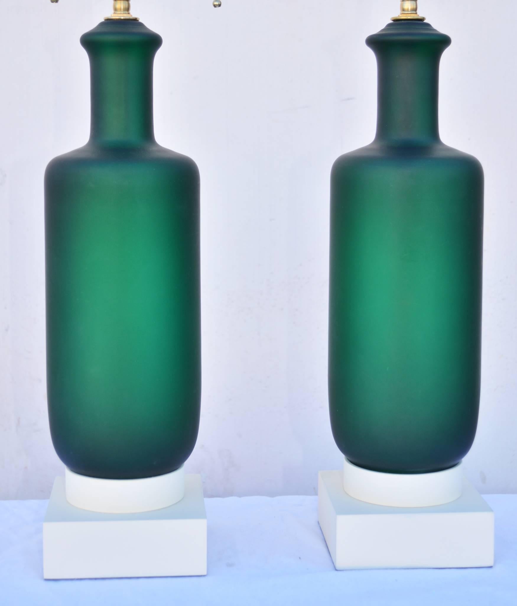A lovely pair of Mid-Century lamps, with stunning green opaline veritable glass bodies on painted wood bases. Newly rewired with cloth French braid wire and brass double cluster sockets. Measures: 19.25" to top of glass. Base is 5.5"