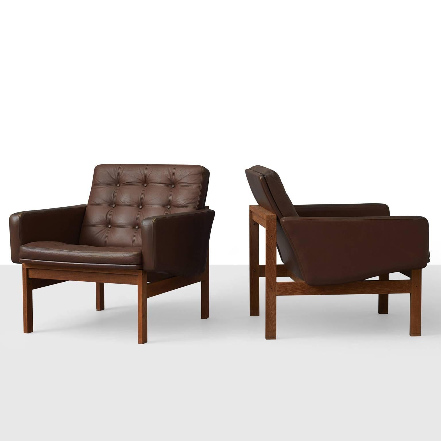 A pair of lounge chairs by Ole Gjerløv - Knudsen & Torben Lind. Each featuring a teak frame, patinated brown leather upholstery and button tufted seat and back cushions.
 