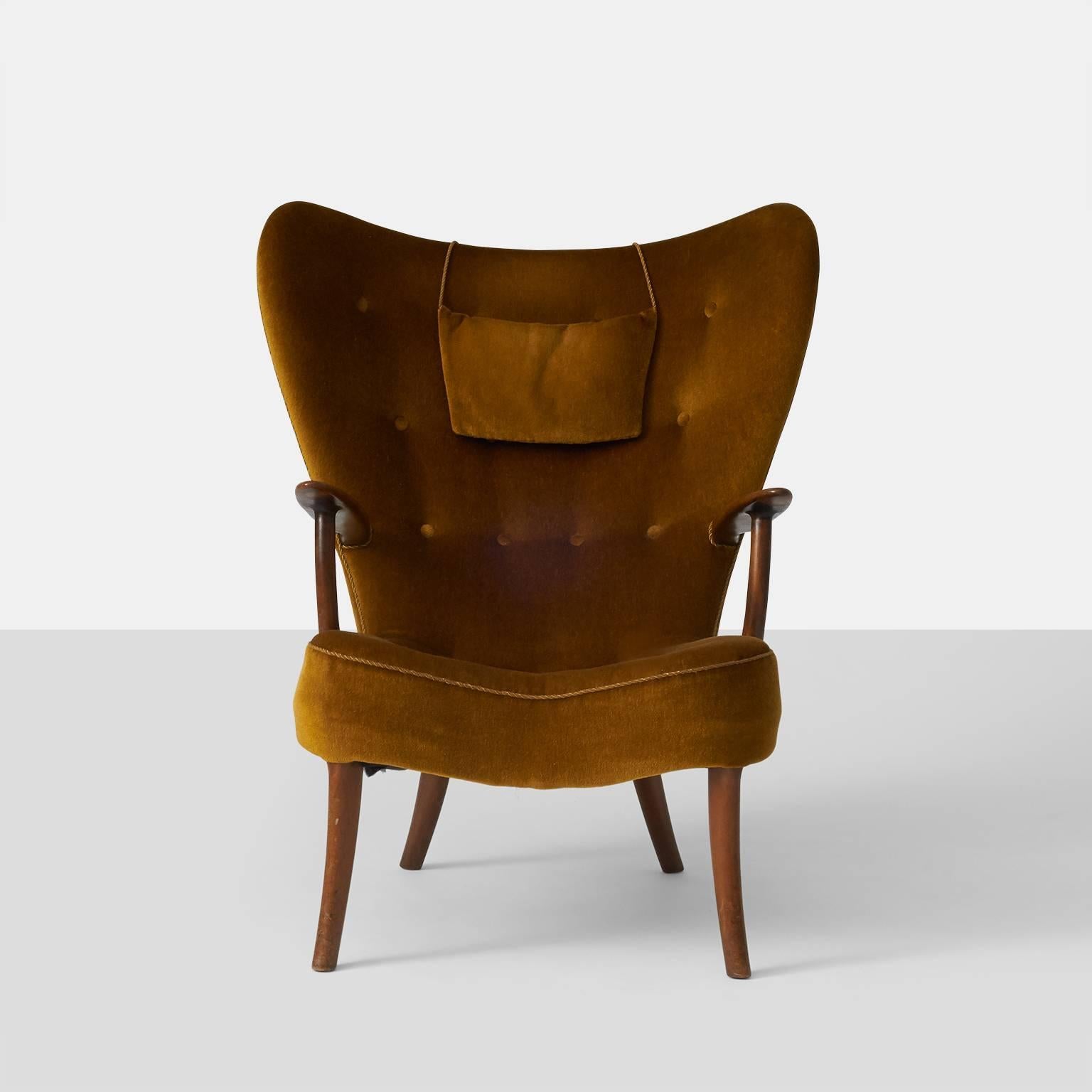 A lounge chair by Acton Schubell and Ib Madsen with legs of stained beech, upholstered in a deep gold velvet with covered buttons.
 