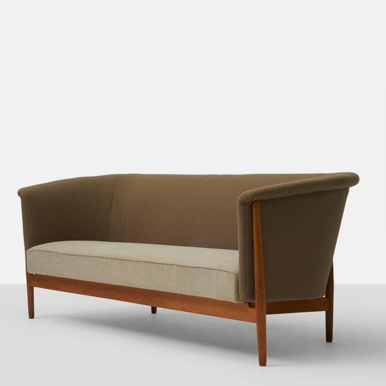 A Nanna Ditzel curved arm sofa upholstered in a two Maharam wool fabrics with an oak wood frame.