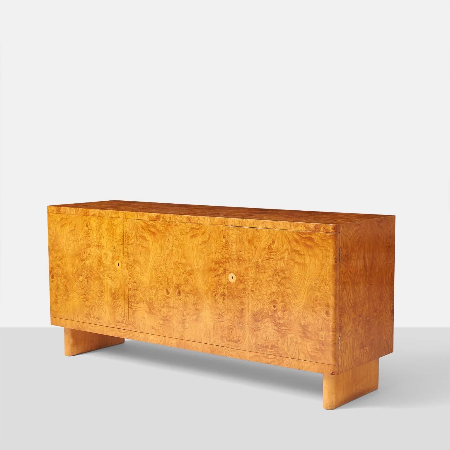 A rare root wood veneered sideboard designed in 1935 by Architect Axel Einar Hjorth. Cabinet has three doors with adjustable shelves on two right sections and the left side having three felt lined pull out drawers. The cabinet retains the original