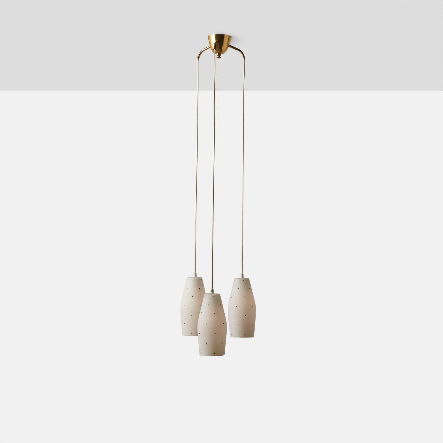 A cascading chandelier by Lisa Johansson-Pape with three white glass shades hand painted with black dots. The canopy is brass each shade has a new US size porcelain socket. Chandelier was made in Finland in the 1960s.