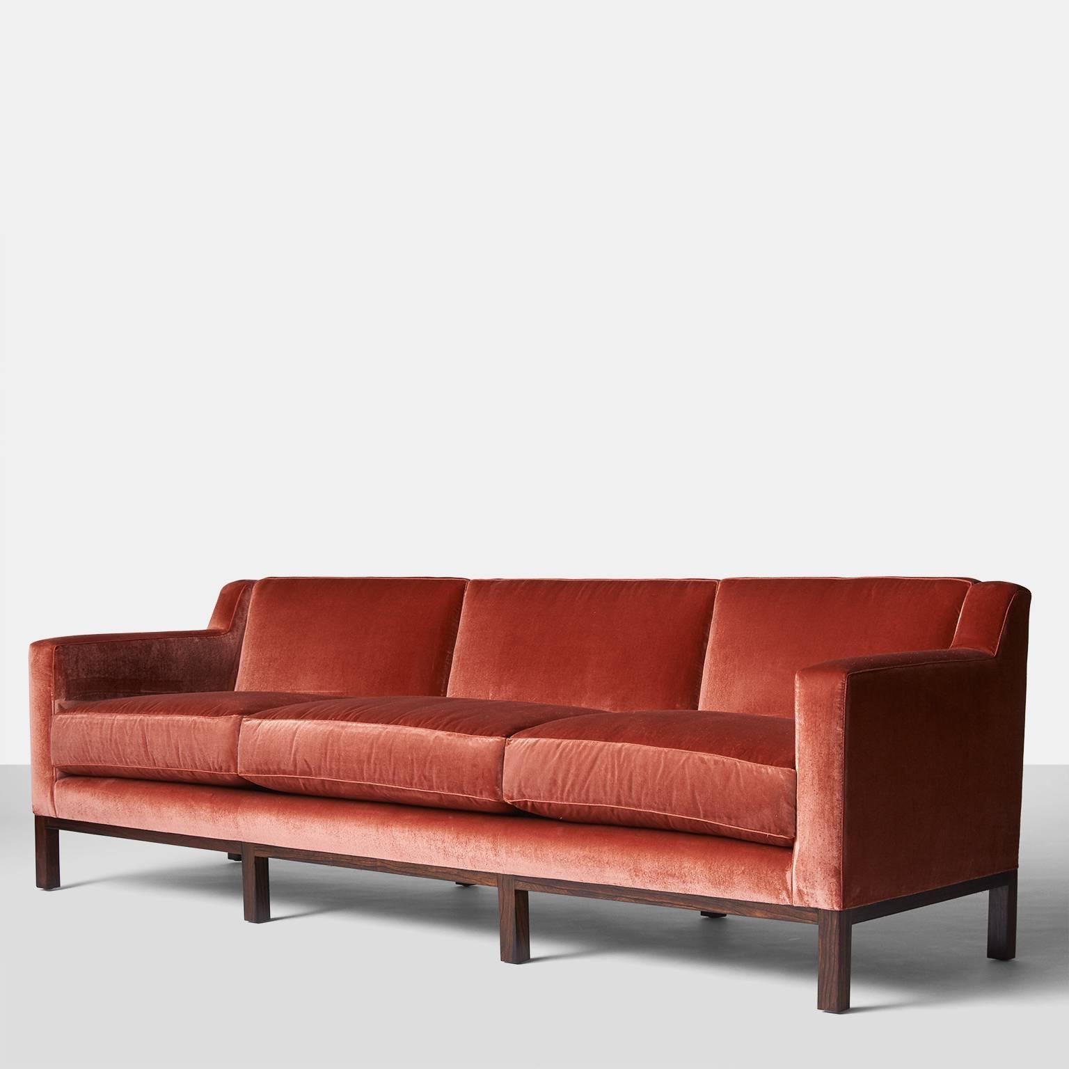 An Edward Wormley sofa for Dunbar circa 1960 with eight mahogany legs. The sofa has been reupholstered in a luxurious coral silk velvet from Holland & Sherry. Three down filled seat cushions and three semi attached back cushions all with